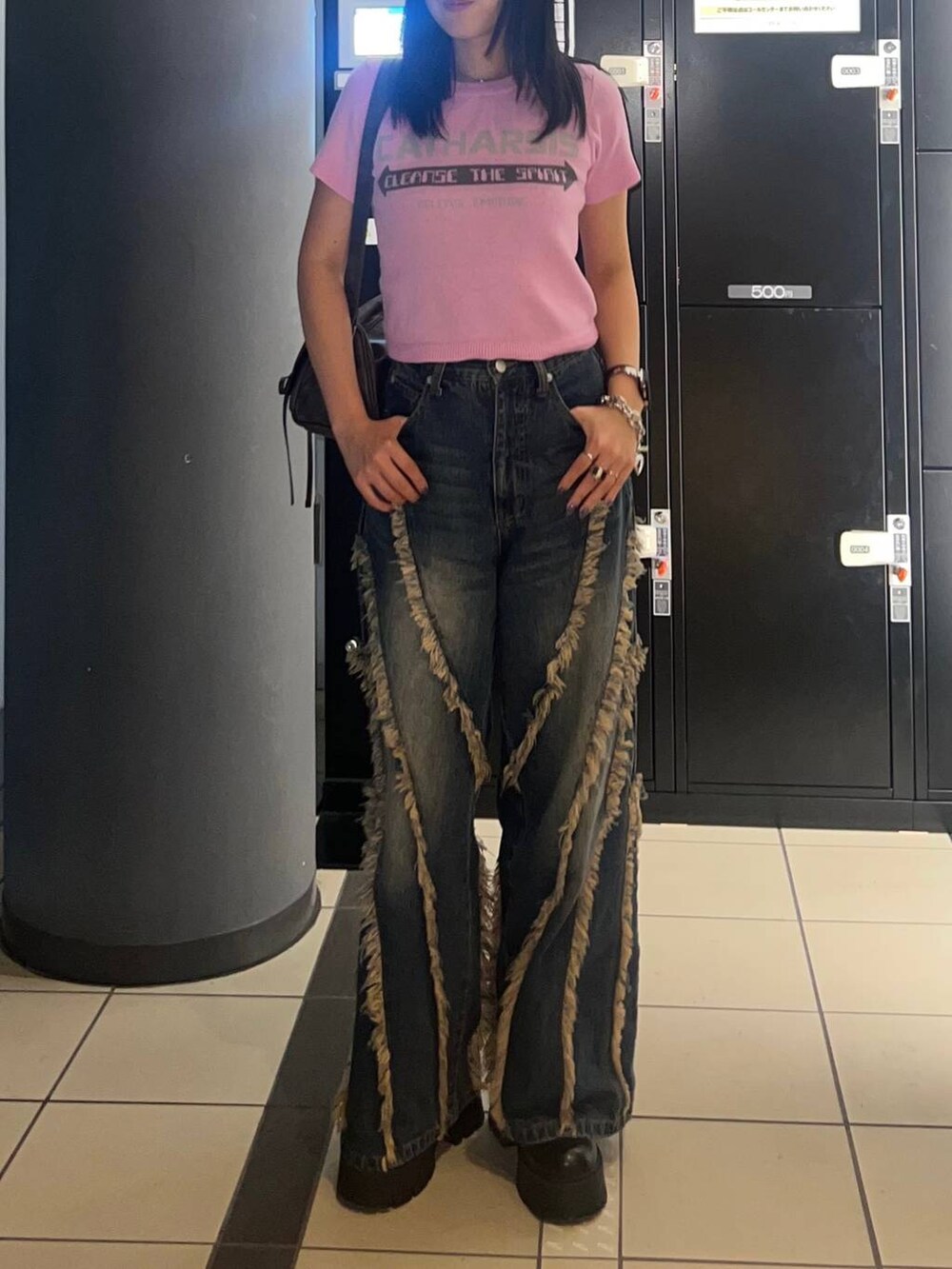 ブルー系のデニムパンツ、ブラウン系のショルダーバッグを着用したレディースの秋コーディネートの2枚目の写真