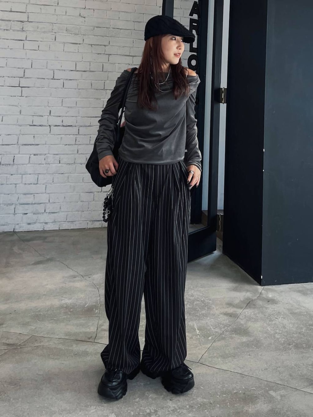 ブラック系のスニーカー、ブラック系のショルダーバッグを着用したレディースの秋コーディネートの2枚目の写真