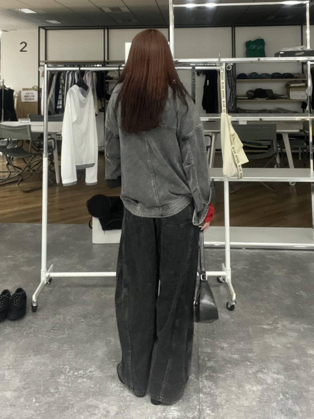 ブラック系のハンドバッグ、ブラック系のブルゾン、ブラック系のデニムパンツを着用したレディースの冬コーディネートの5枚目の写真