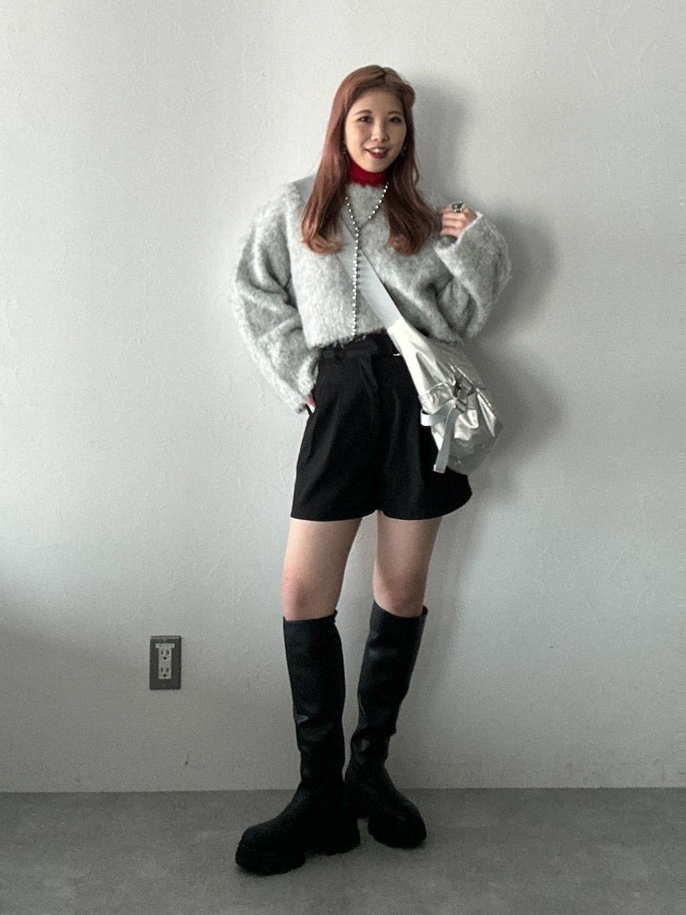 シルバー系のショルダーバッグ、ブラック系のブーツ、ブラック系のその他パンツを着用したレディースの冬コーディネートの2枚目の写真