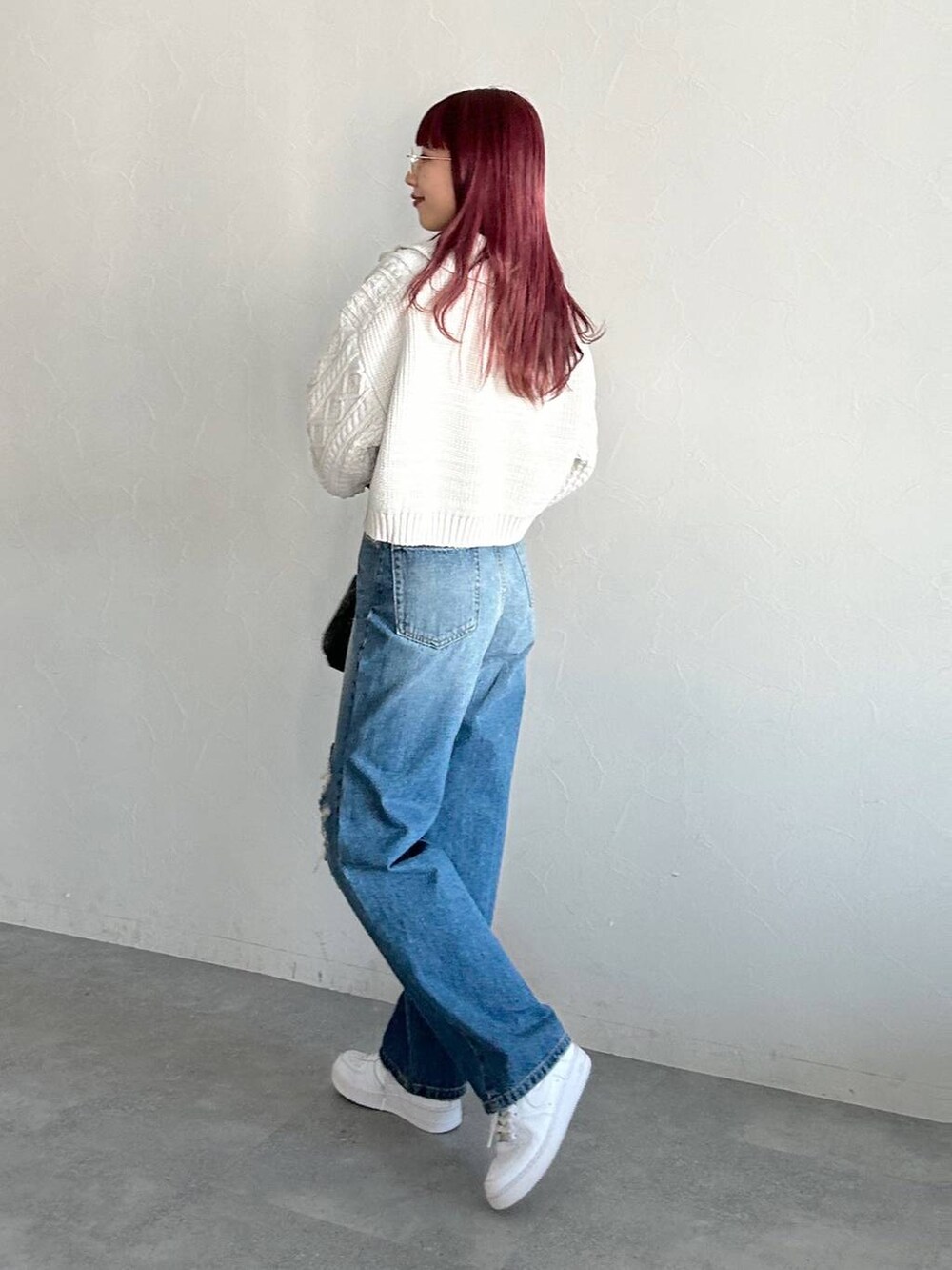 ブルー系のデニムパンツ、ブラック系のショルダーバッグ、グレー系のニット/セーターを着用したレディースの冬コーディネートの3枚目の写真