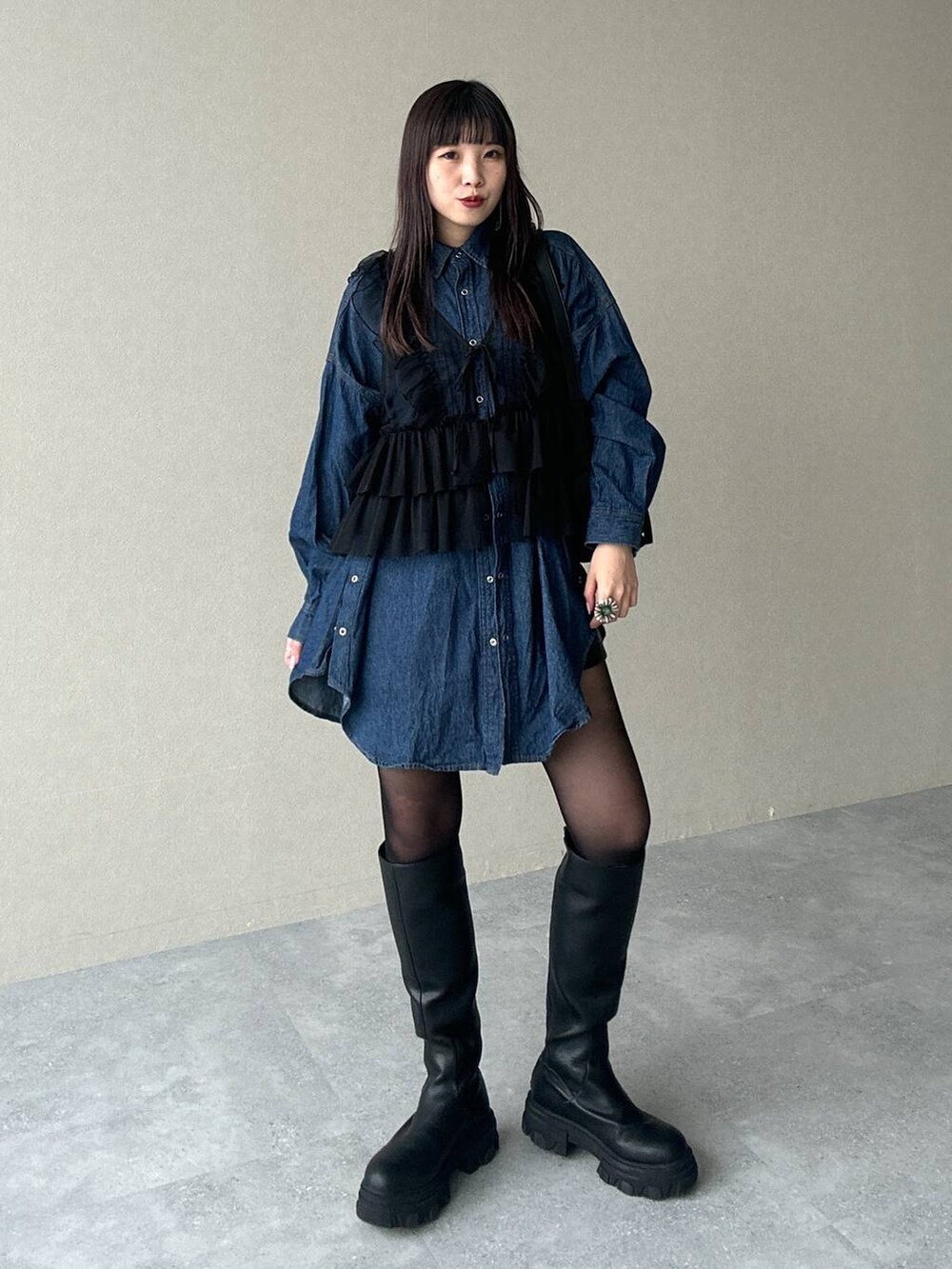 ブラック系のショルダーバッグ、ブルー系のシャツ/ブラウス、ブラック系のブーツを着用したレディースの春コーディネートの2枚目の写真