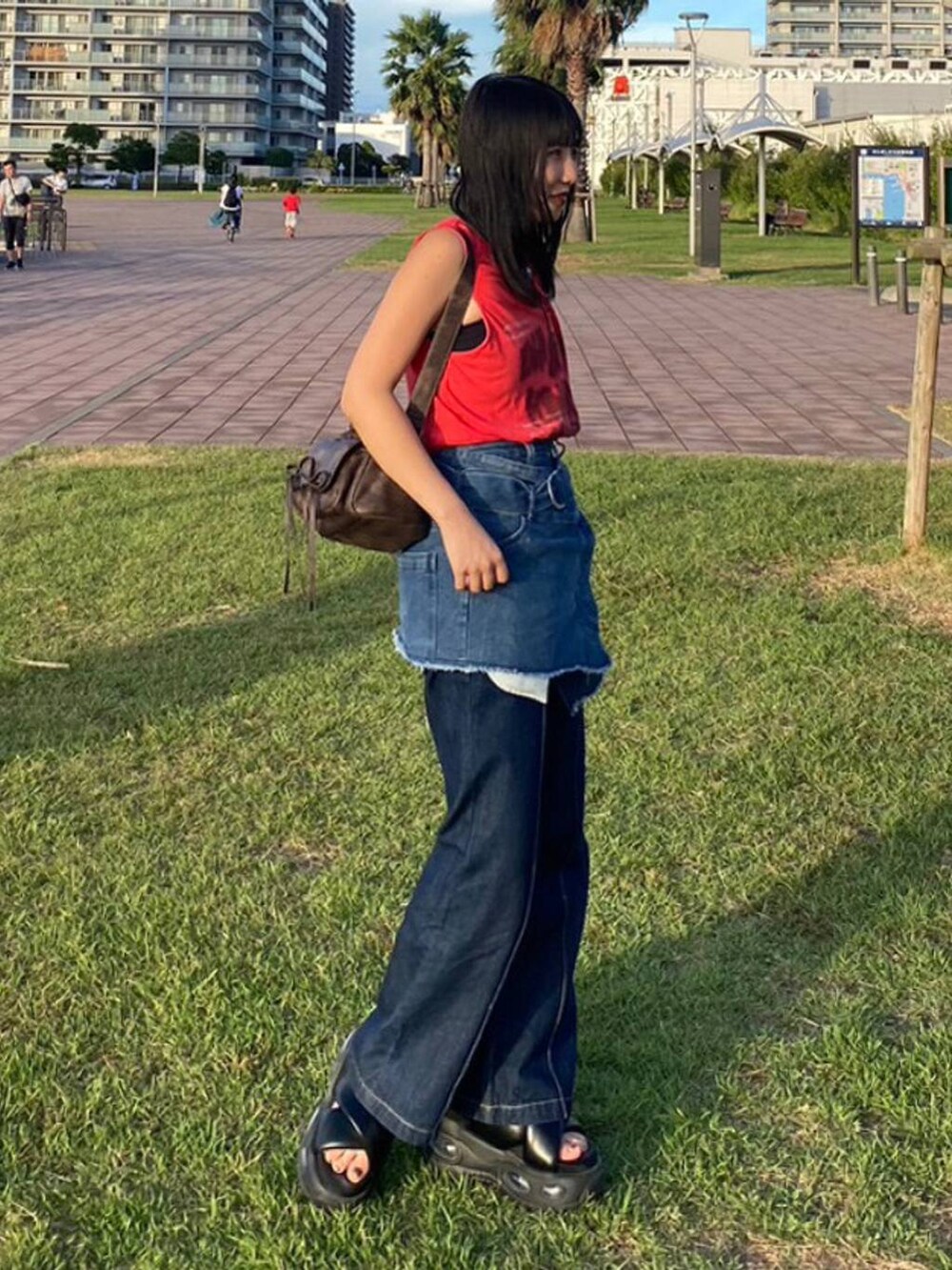 ブラウン系のショルダーバッグ、レッド系のTシャツ/カットソー、ブルー系のベルトを着用したレディースの秋コーディネートの2枚目の写真