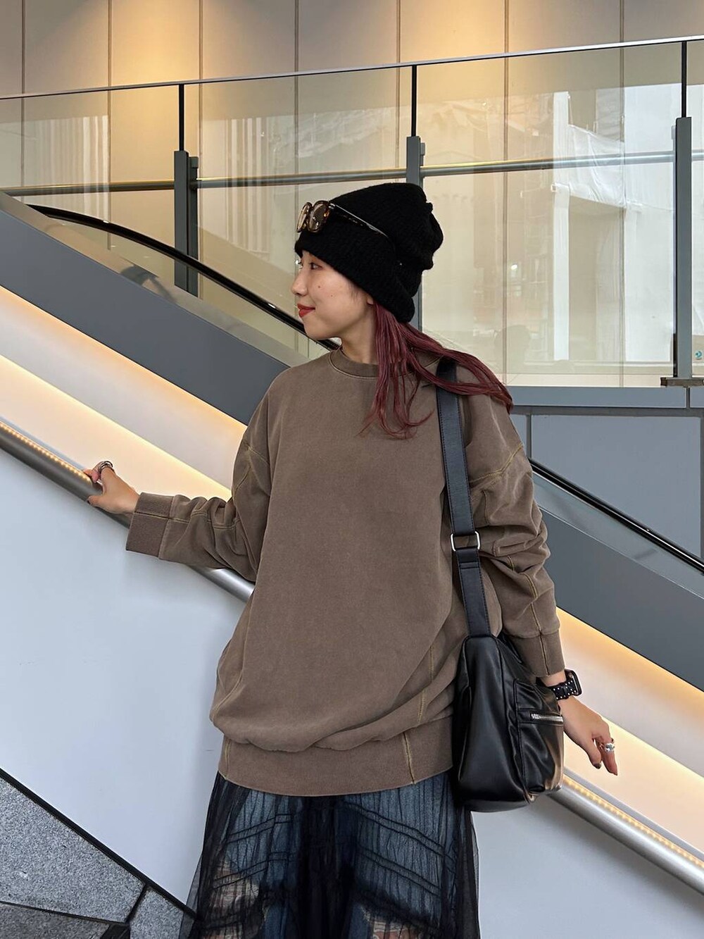 ブラウン系のスウェット、ブルー系のデニムパンツ、ブラック系のブーツを着用したレディースの秋コーディネートの2枚目の写真