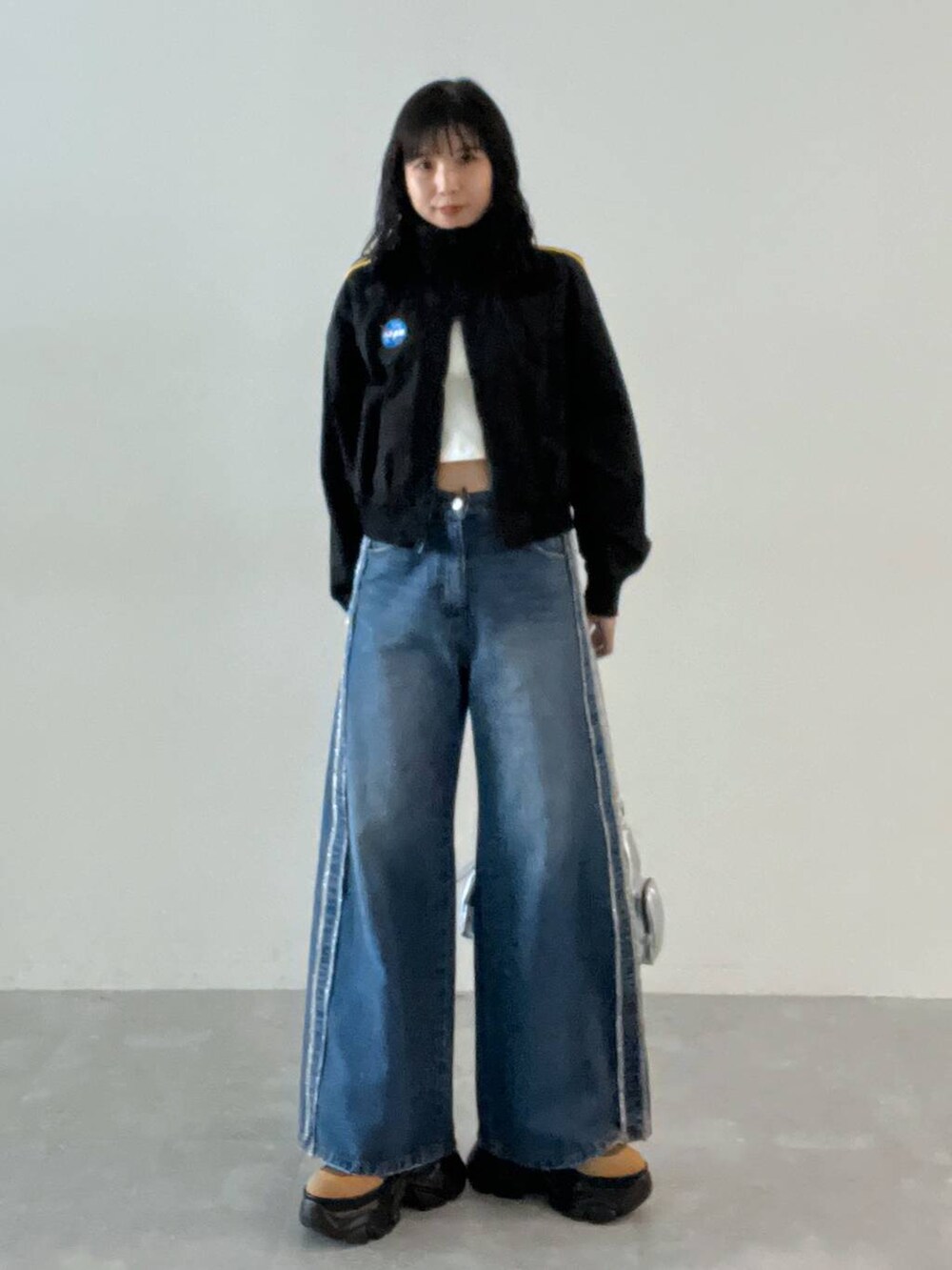 ホワイト系のキャミソール、ブラウン系のブーツ、シルバー系のショルダーバッグを着用したレディースの秋コーディネートの3枚目の写真