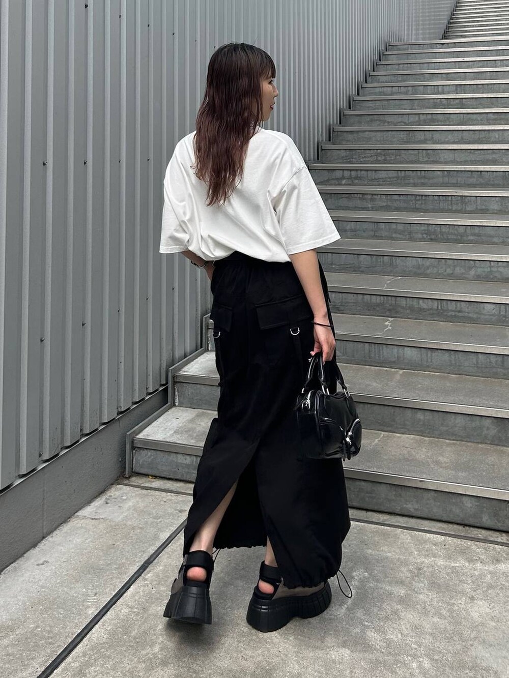 その他のスニーカー、ブラック系のスカート、ブラック系のボストンバッグを着用したレディースの夏コーディネートの2枚目の写真