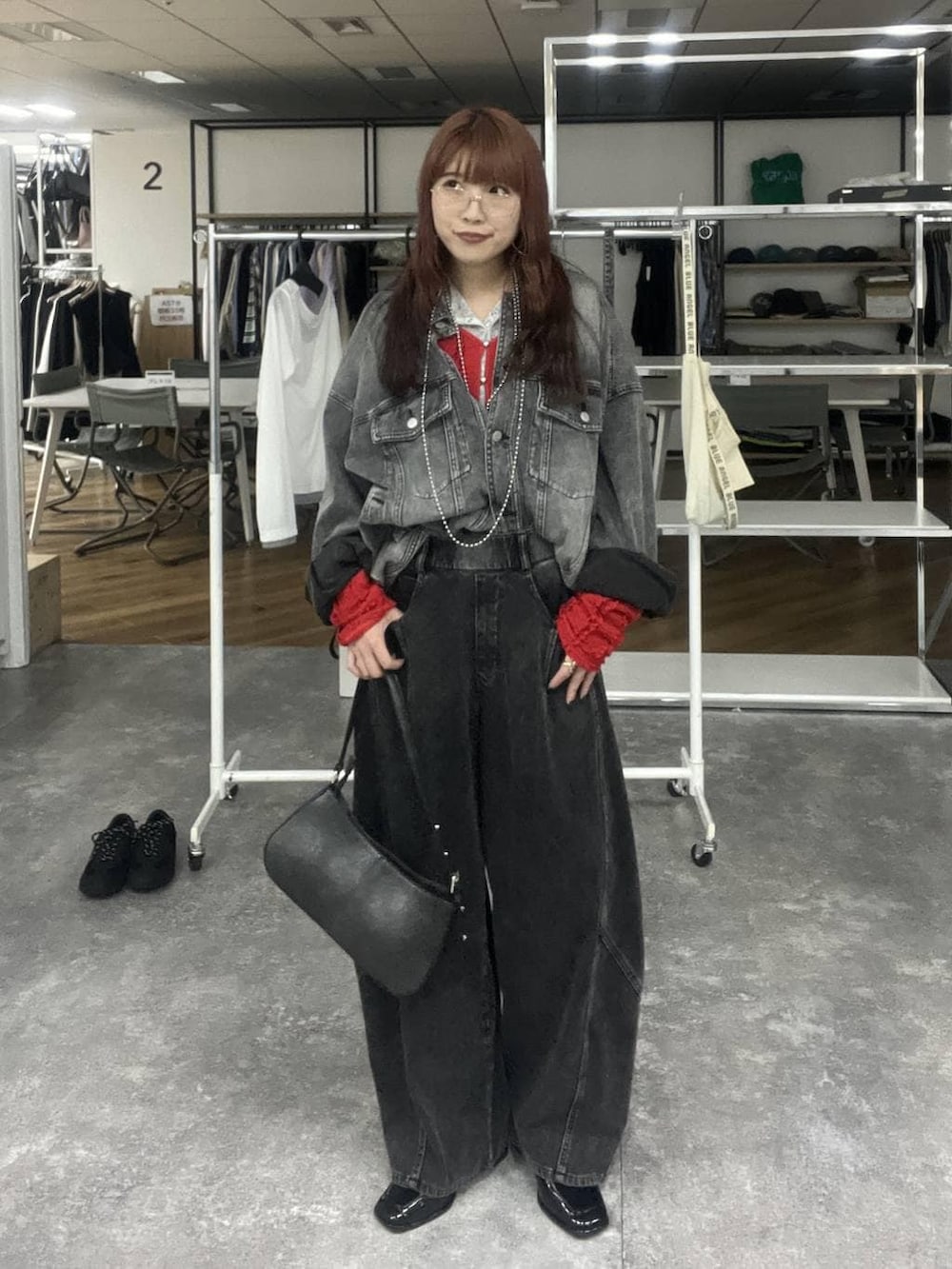 ブラック系のハンドバッグ、ブラック系のブルゾン、ブラック系のデニムパンツを着用したレディースの冬コーディネートの3枚目の写真