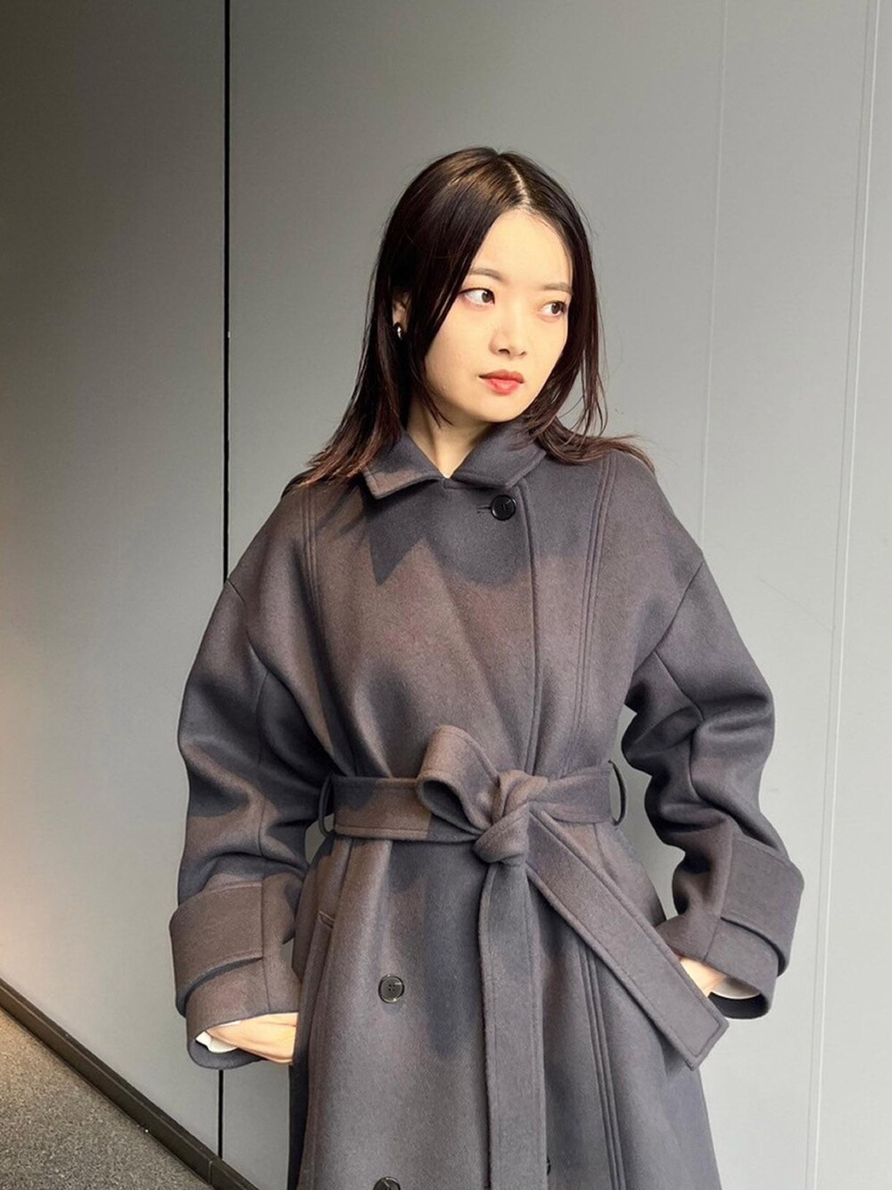 グレー系のステンカラーコートを着用したレディースの秋コーディネートの4枚目の写真