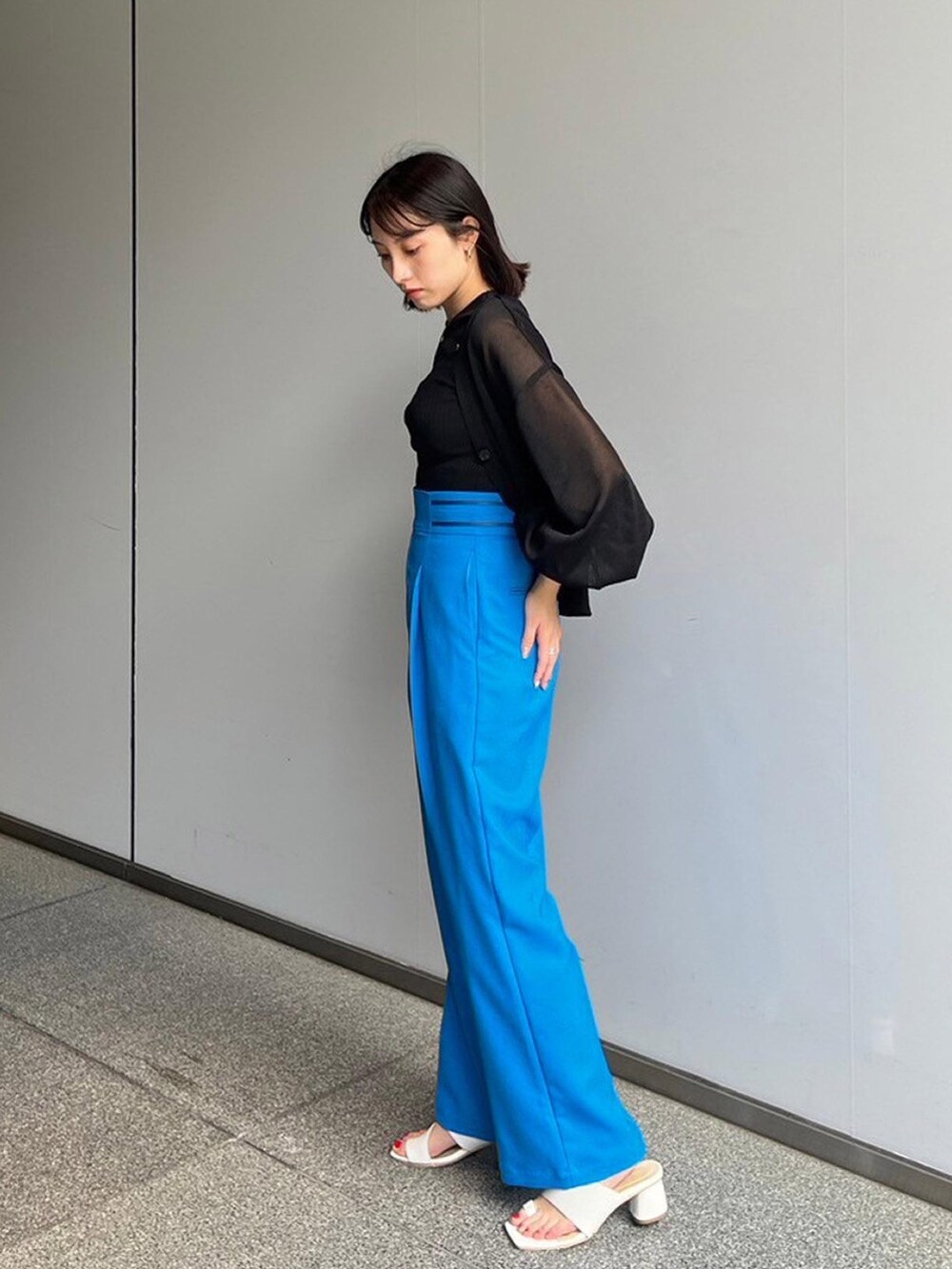 ブラック系のタンクトップ、ブラック系のカーディガン/ボレロ、ブルー系のスラックスを着用したレディースの夏コーディネートの2枚目の写真