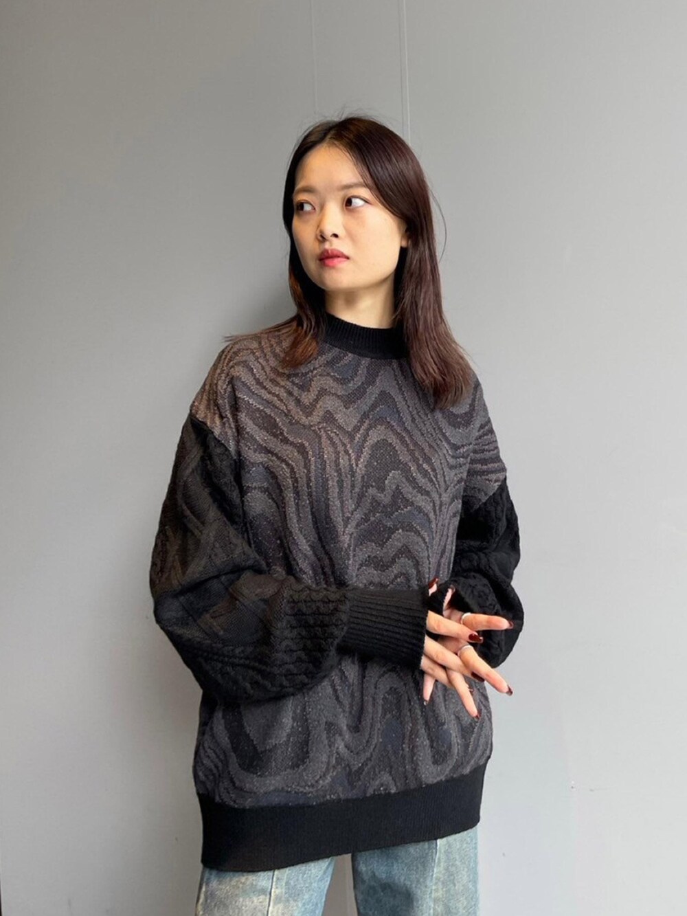 ブラック系のニット/セーター、ブルー系のデニムパンツを着用したレディースの秋コーディネートの4枚目の写真