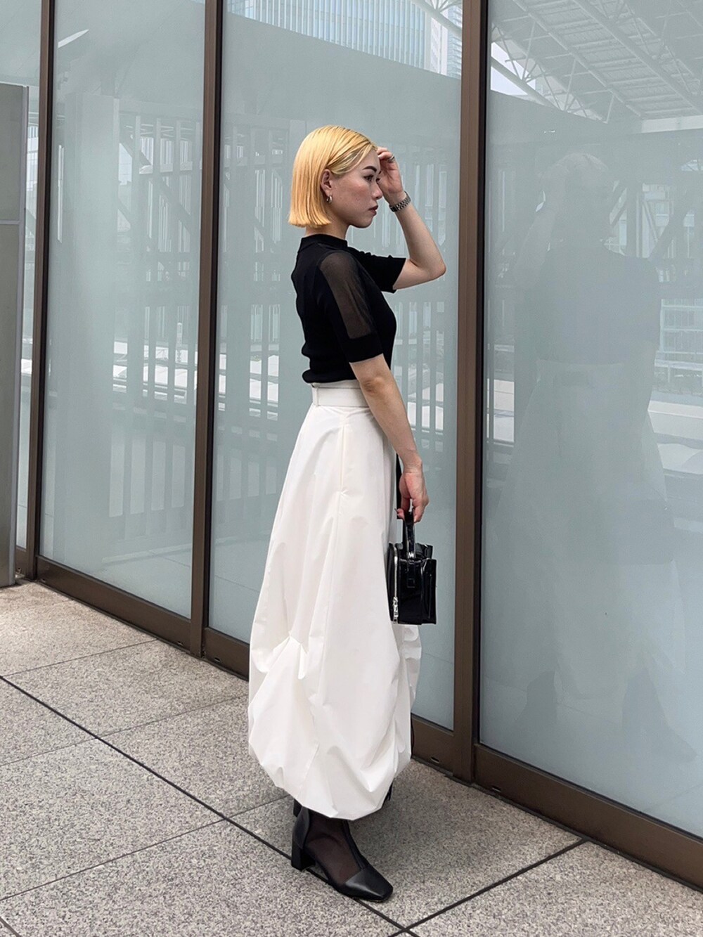 ブラック系のニット/セーター、ホワイト系のスカートを着用したレディースの夏コーディネートの2枚目の写真