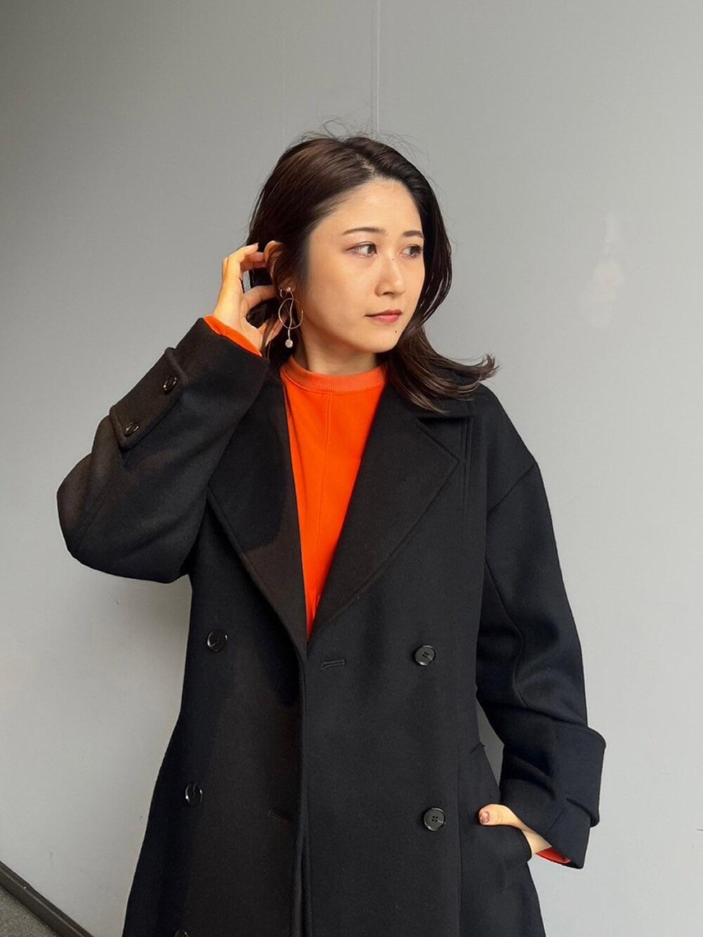 ブラック系のステンカラーコートを着用したレディースの秋コーディネートの4枚目の写真