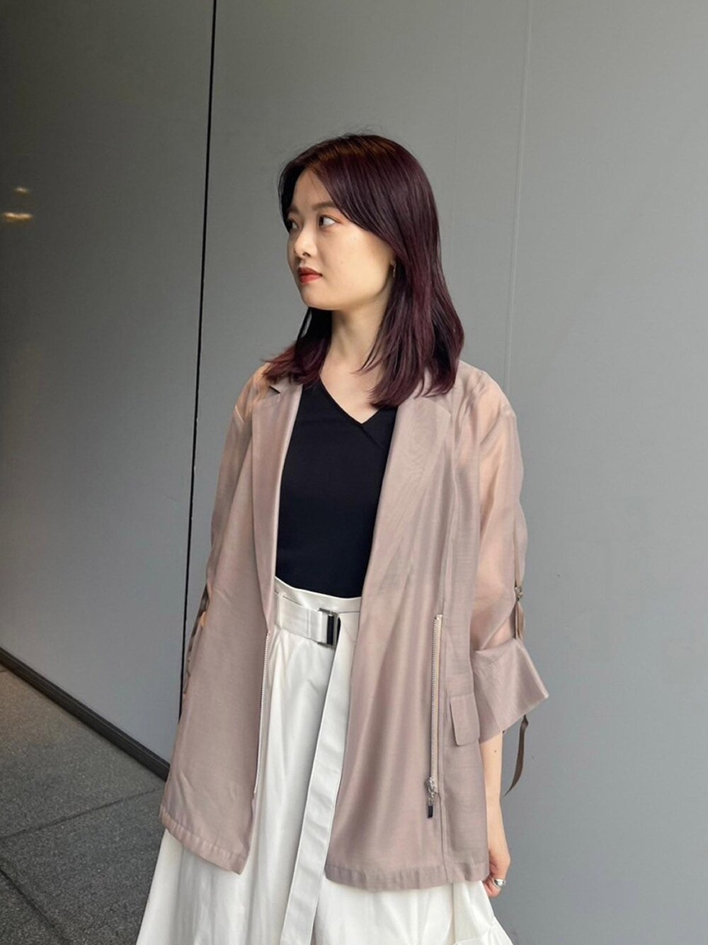 ベージュ系のテーラードジャケット、ホワイト系のスカート、ブラック系のサンダルを着用したレディースの夏コーディネートの2枚目の写真