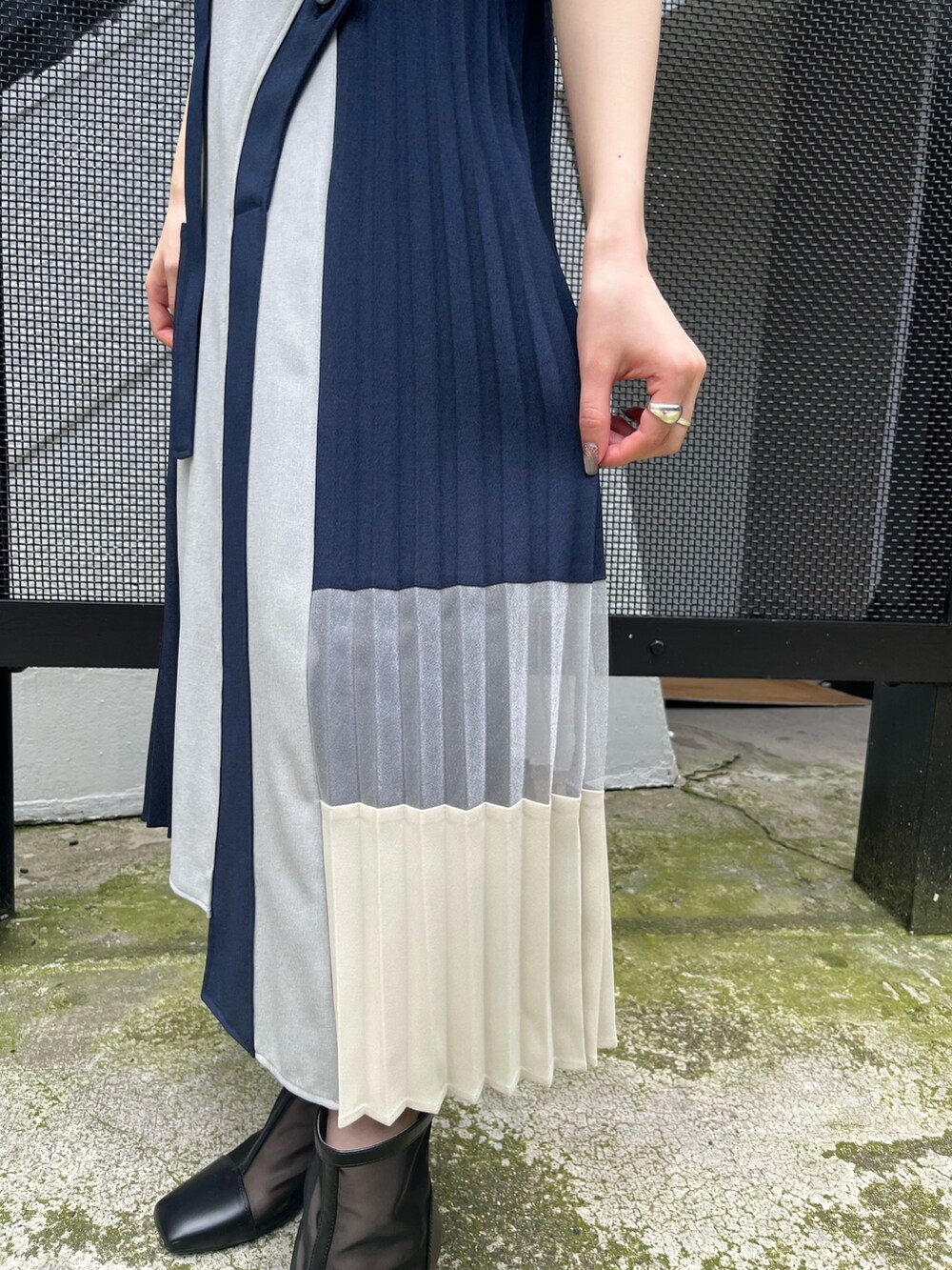 ブラック系のニット/セーター、ブルー系のスカート、ブラック系のブーツを着用したレディースの春コーディネートの6枚目の写真