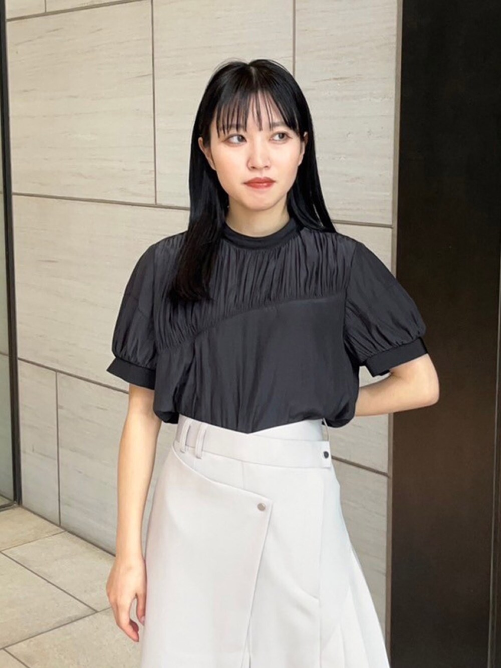 ベージュ系のスカート、ブラック系のシャツ/ブラウスを着用したレディースの春コーディネートの5枚目の写真