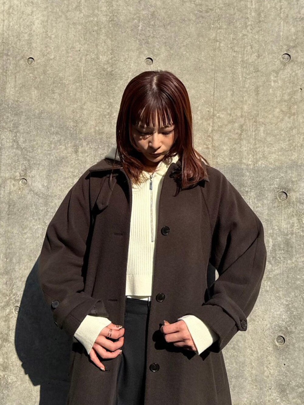 ブラウン系のステンカラーコートを着用したレディースの秋コーディネートの4枚目の写真