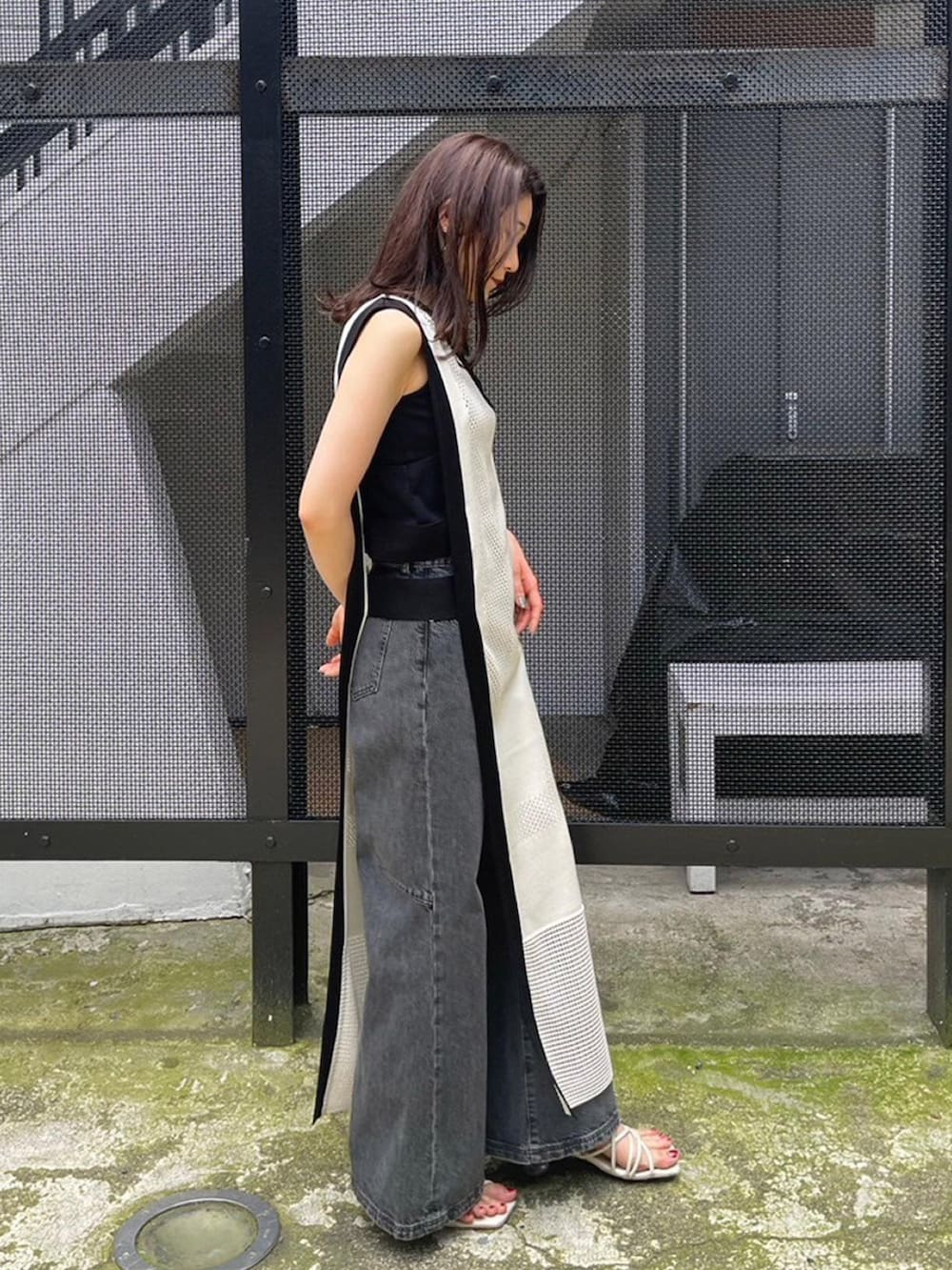 ホワイト系のワンピース、ブラック系のタンクトップ、ブラック系のデニムパンツを着用したレディースの春コーディネートの2枚目の写真