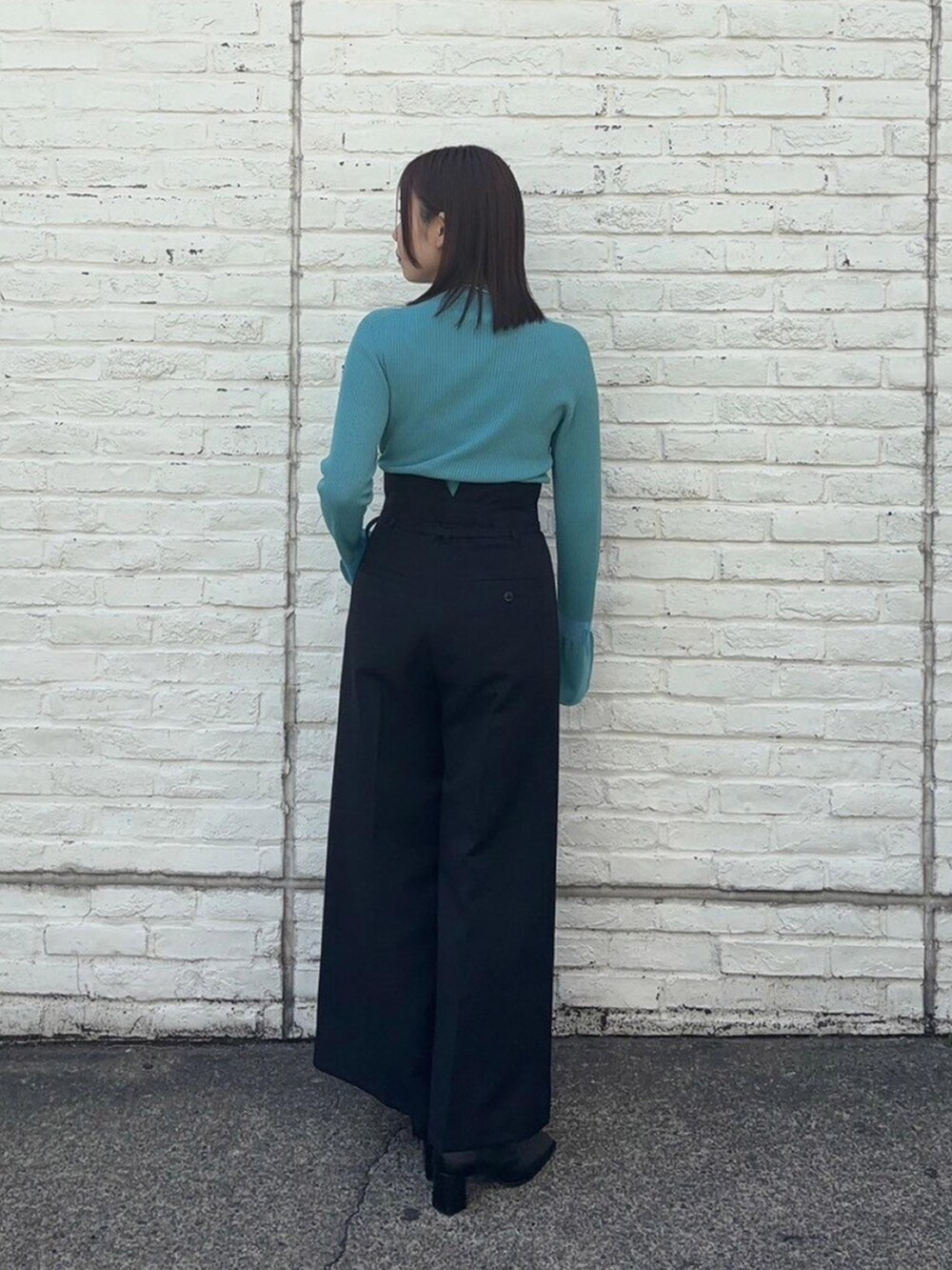 ブルー系のニット/セーター、ブラック系のスラックスを着用したレディースの春コーディネートの3枚目の写真