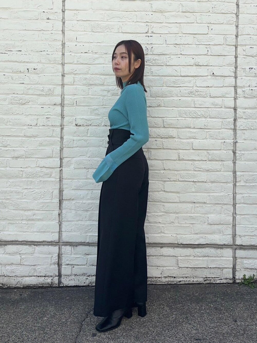 ブルー系のニット/セーター、ブラック系のスラックスを着用したレディースの春コーディネートの2枚目の写真