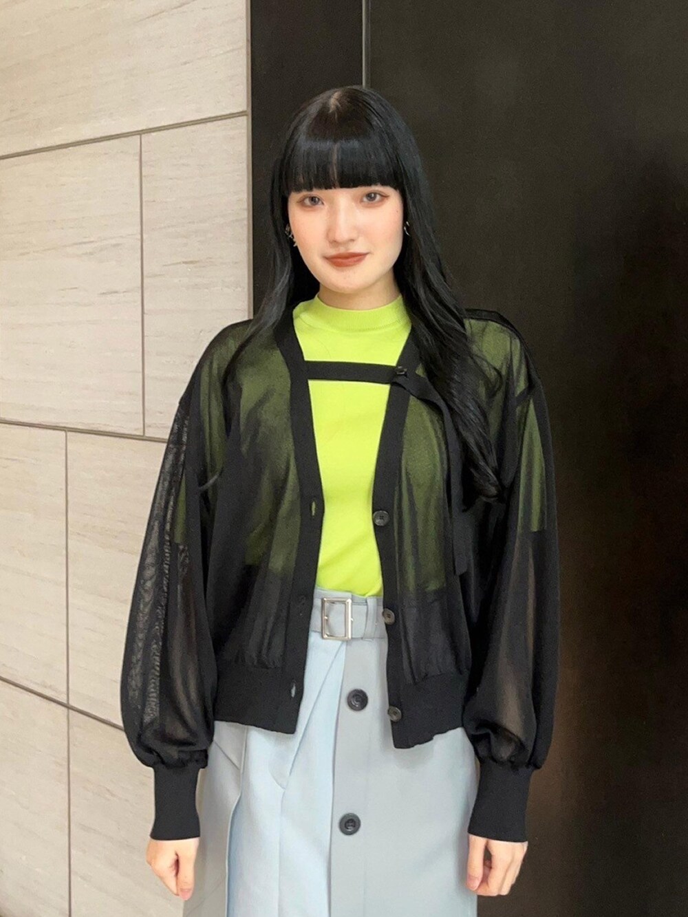 グレー系のスカート、ブラック系のカーディガン/ボレロ、グリーン系のニット/セーターを着用したレディースの春コーディネートの5枚目の写真