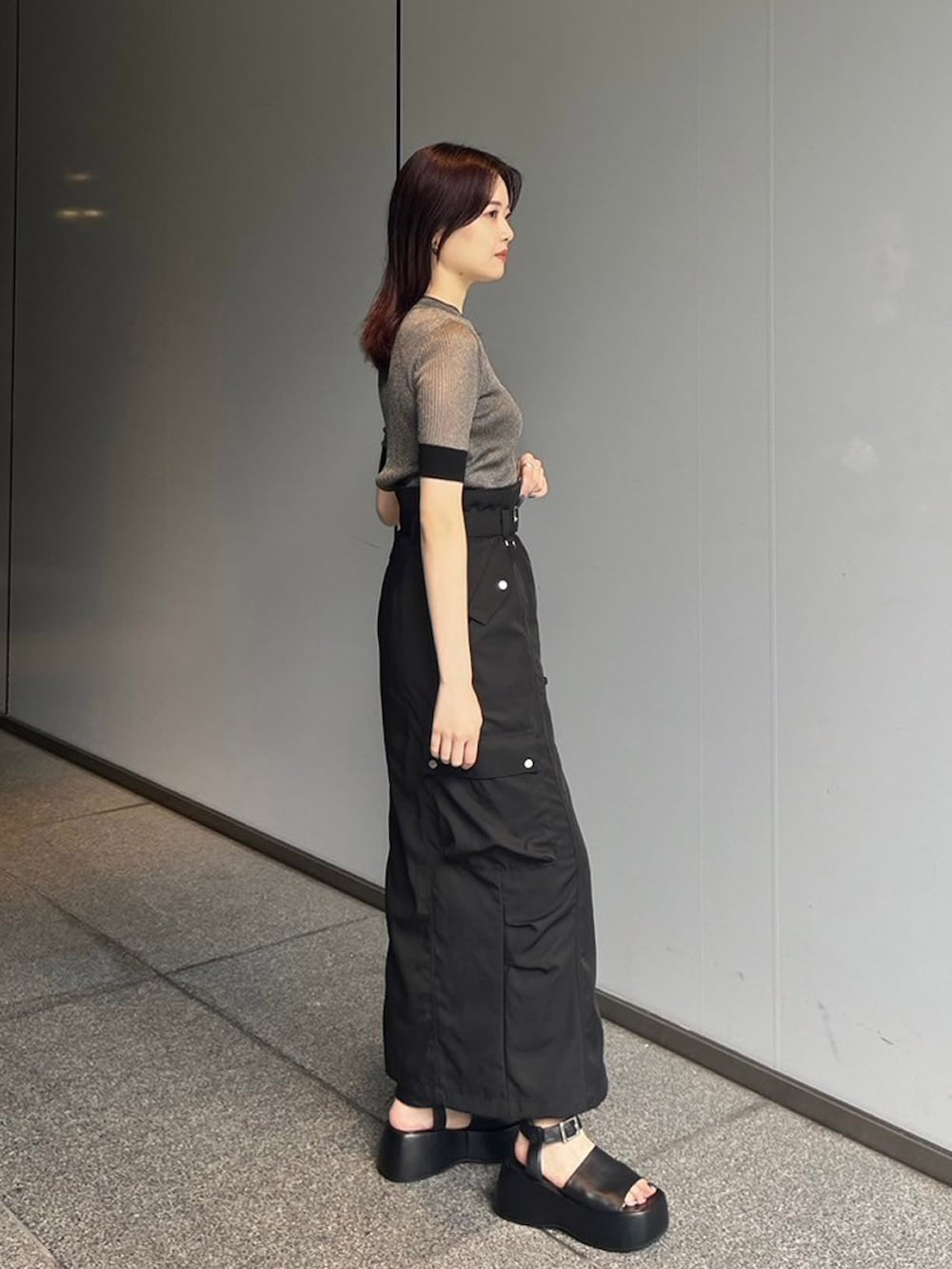 ゴールド系のニット/セーター、ブラック系のスカートを着用したレディースの夏コーディネートの3枚目の写真