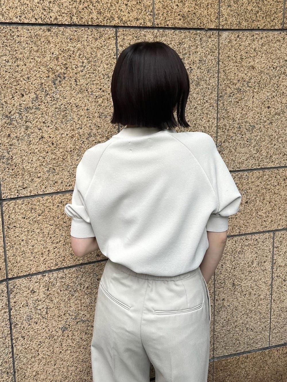 ベージュ系のニット/セーター、ベージュ系のスラックスを着用したレディースの春コーディネートの6枚目の写真