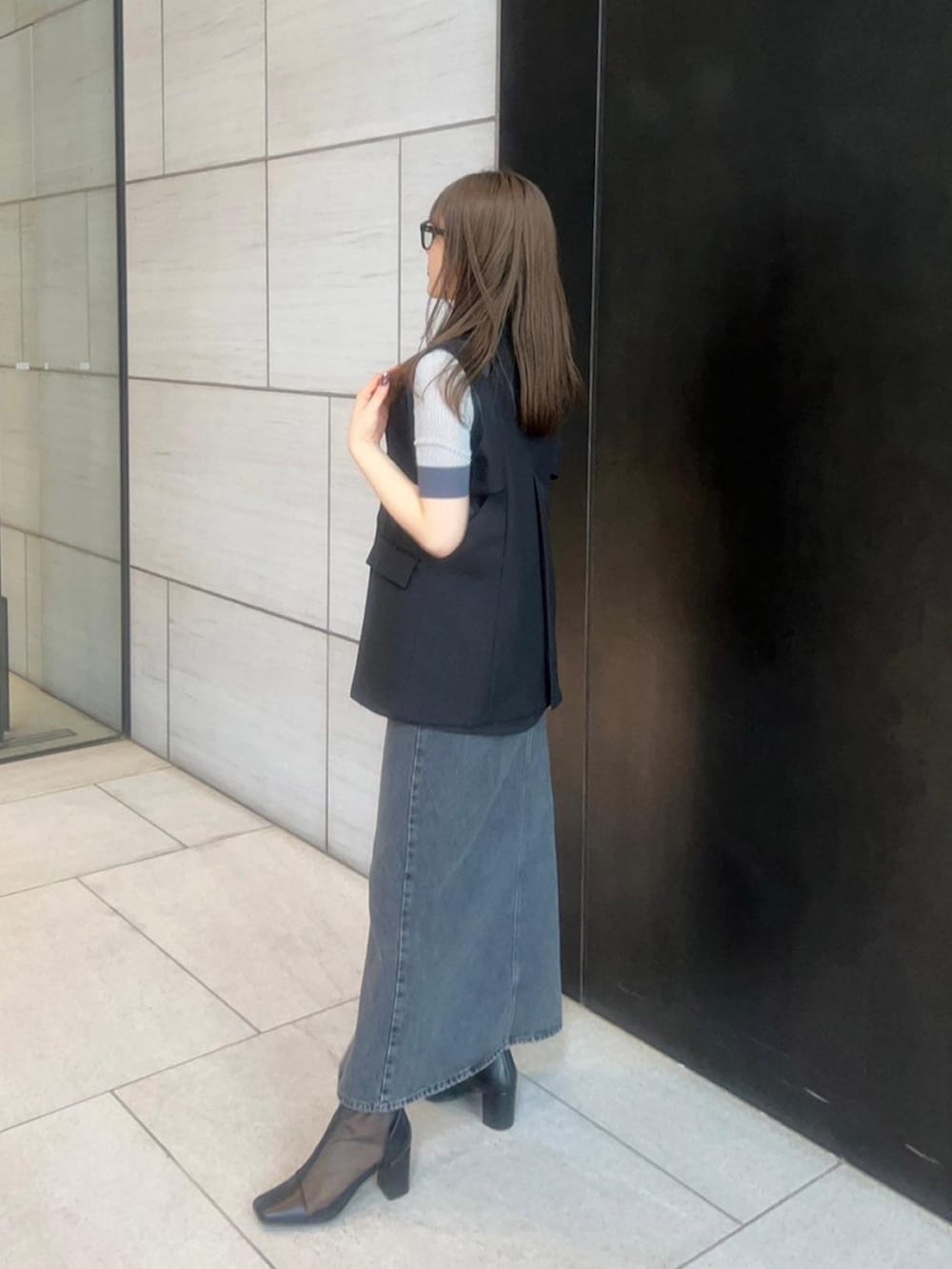 ブラック系のベストを着用したレディースの春コーディネートの2枚目の写真