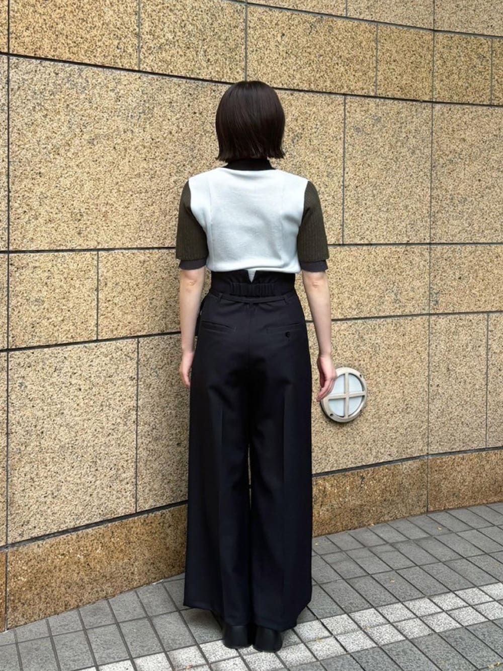 グレー系のニット/セーター、ブラック系のスラックスを着用したレディースの春コーディネートの3枚目の写真