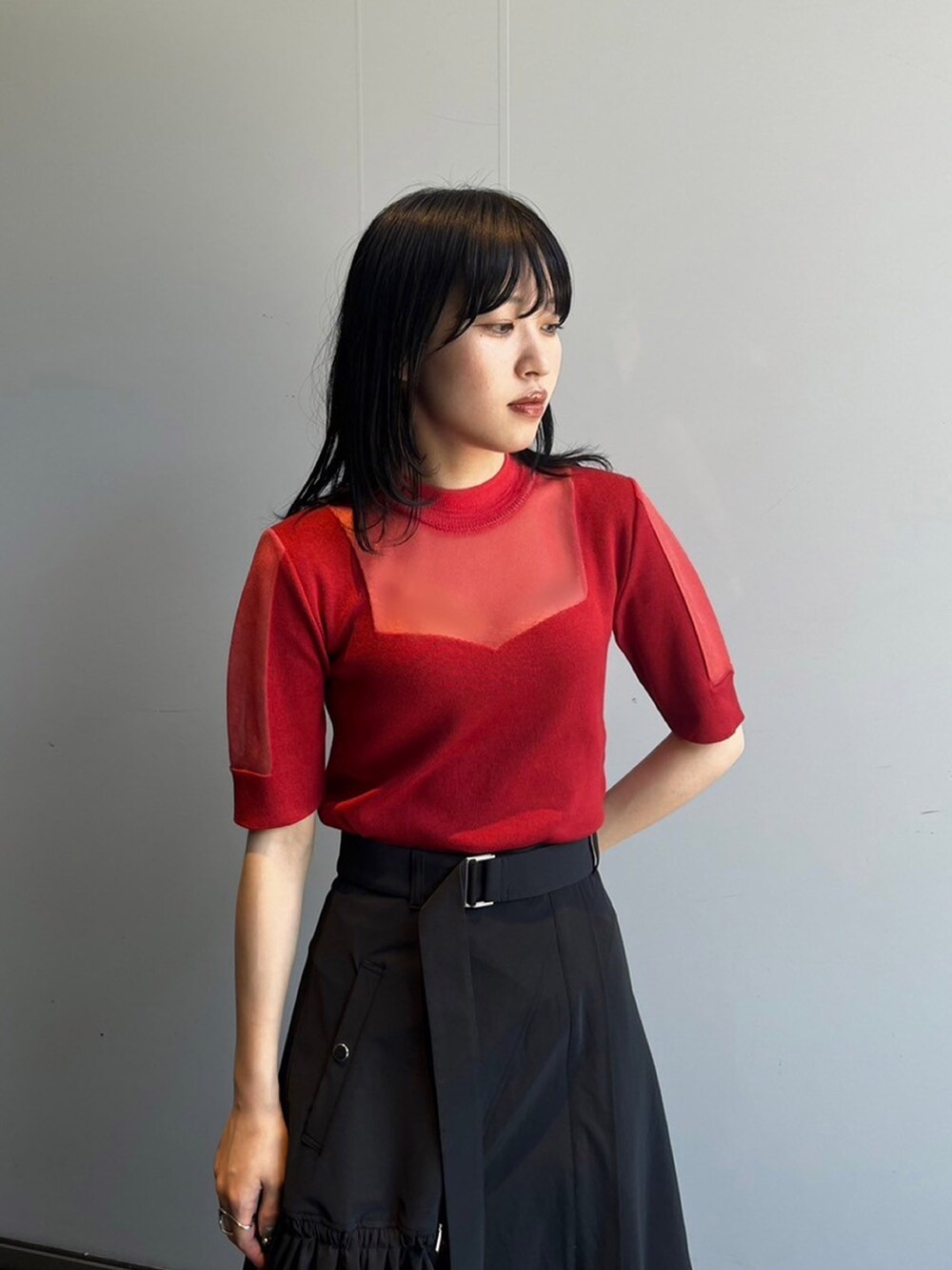 レッド系のニット/セーター、ブラック系のスカートを着用したレディースの夏コーディネートの2枚目の写真