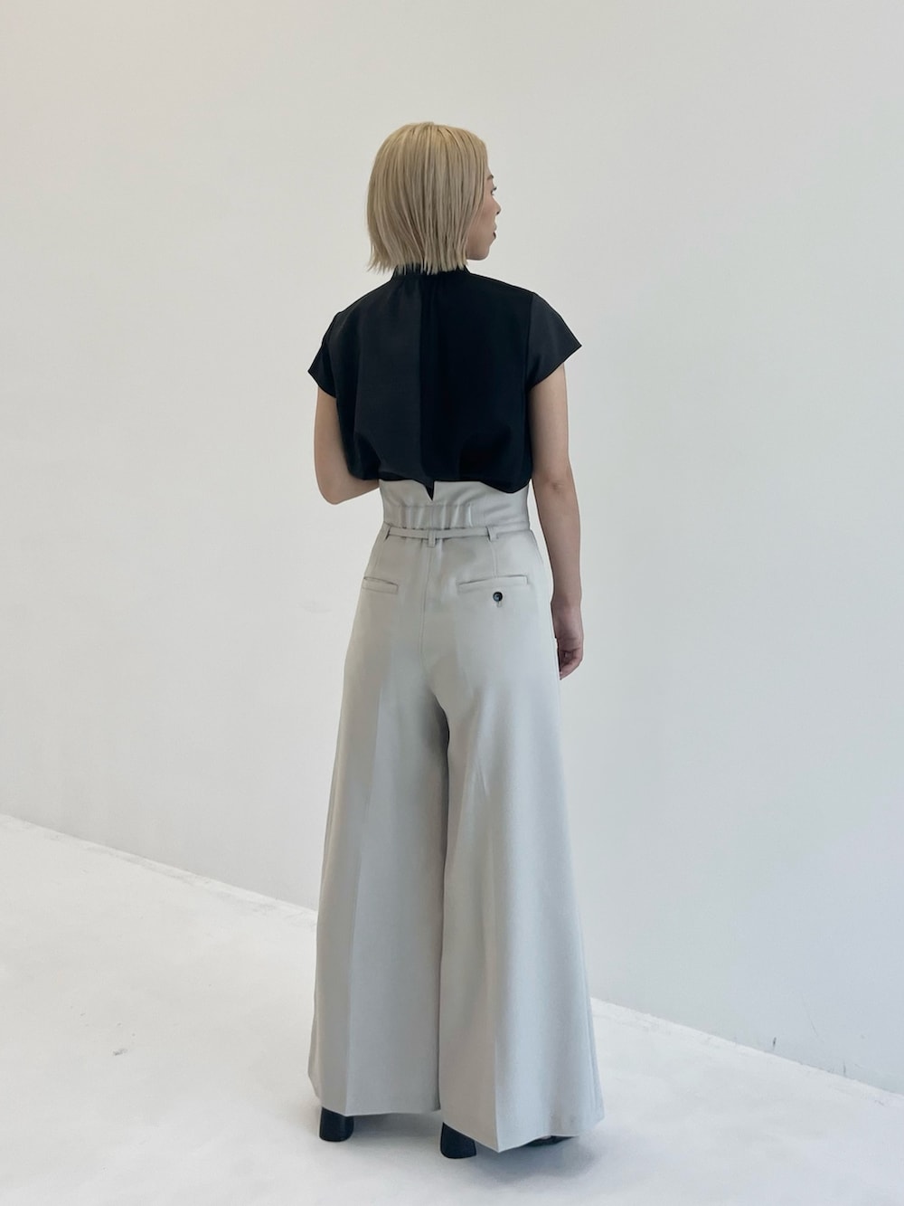 ブラック系のシャツ/ブラウス、グレー系のスラックスを着用したレディースの夏コーディネートの2枚目の写真