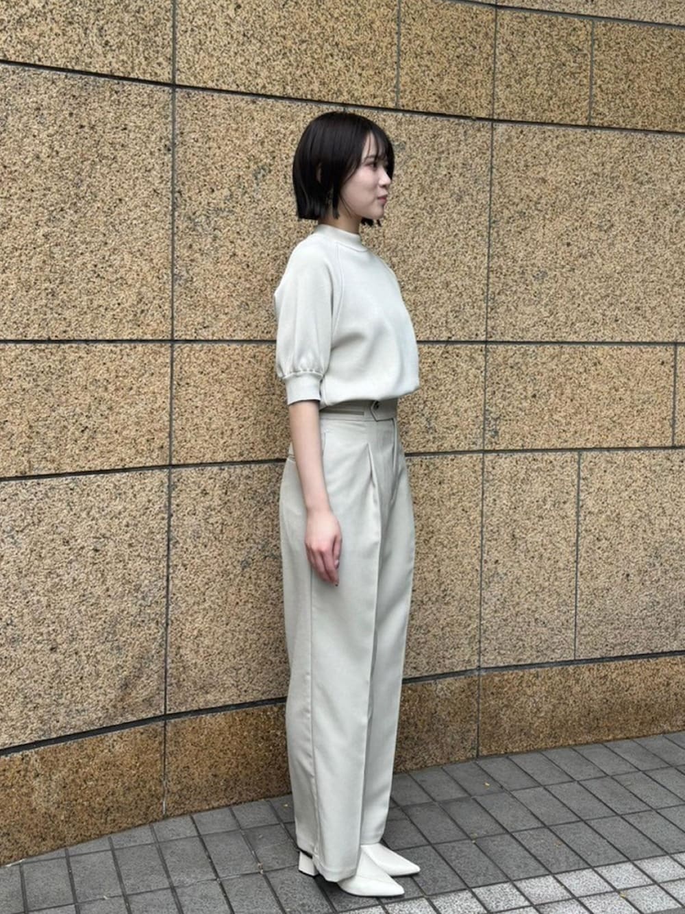 ベージュ系のニット/セーター、ベージュ系のスラックスを着用したレディースの春コーディネートの4枚目の写真