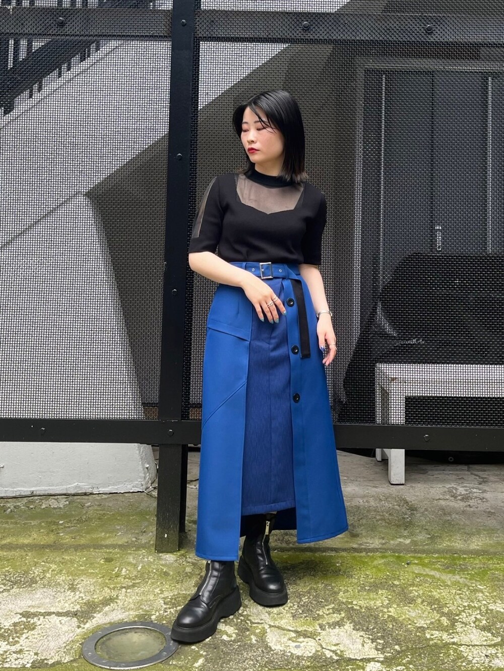ブラック系のニット/セーター、ブルー系のスカートを着用したレディースの春コーディネートの2枚目の写真