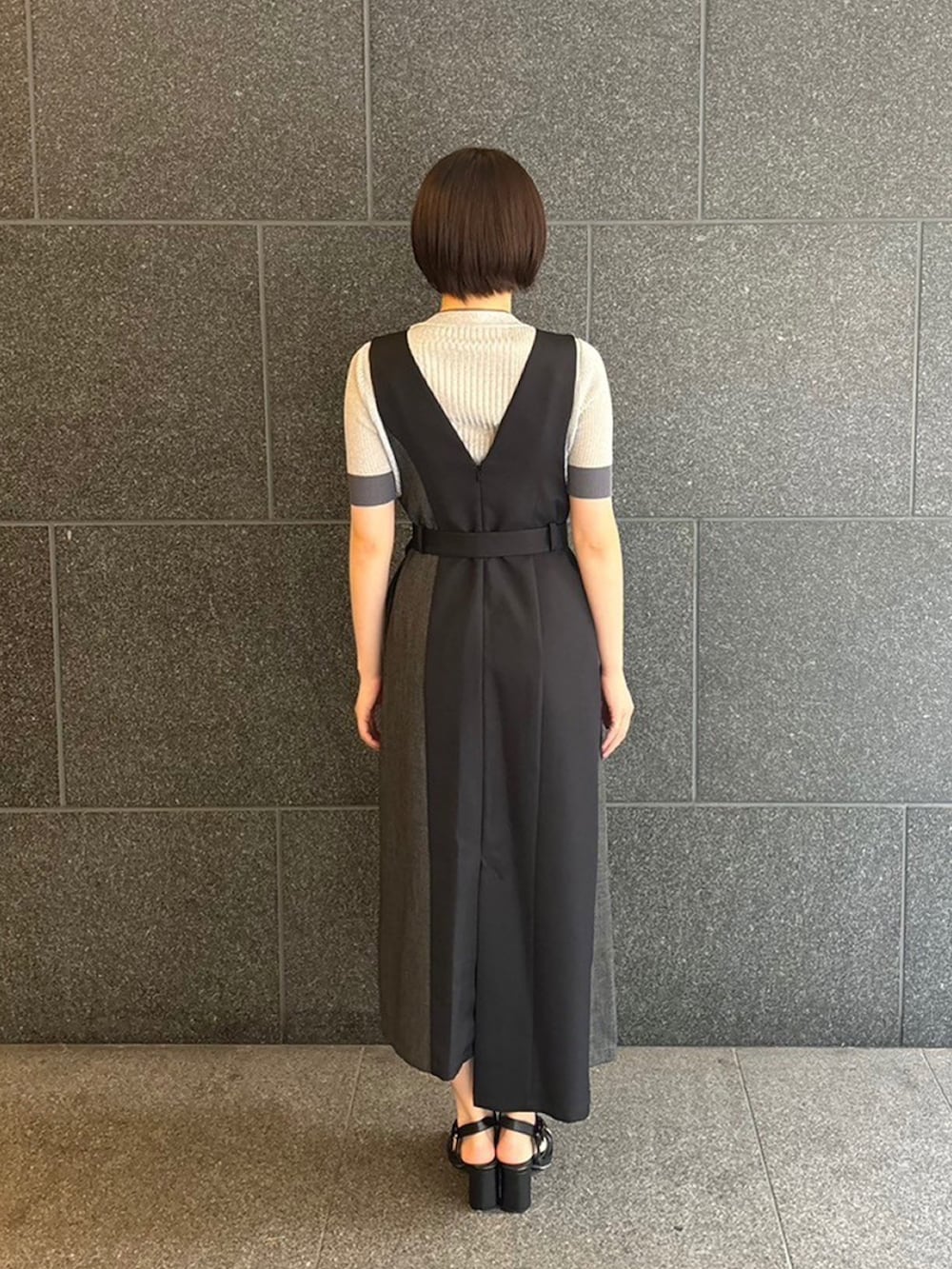 シルバー系のニット/セーター、ブラック系のジャンパースカートを着用したレディースの夏コーディネートの2枚目の写真