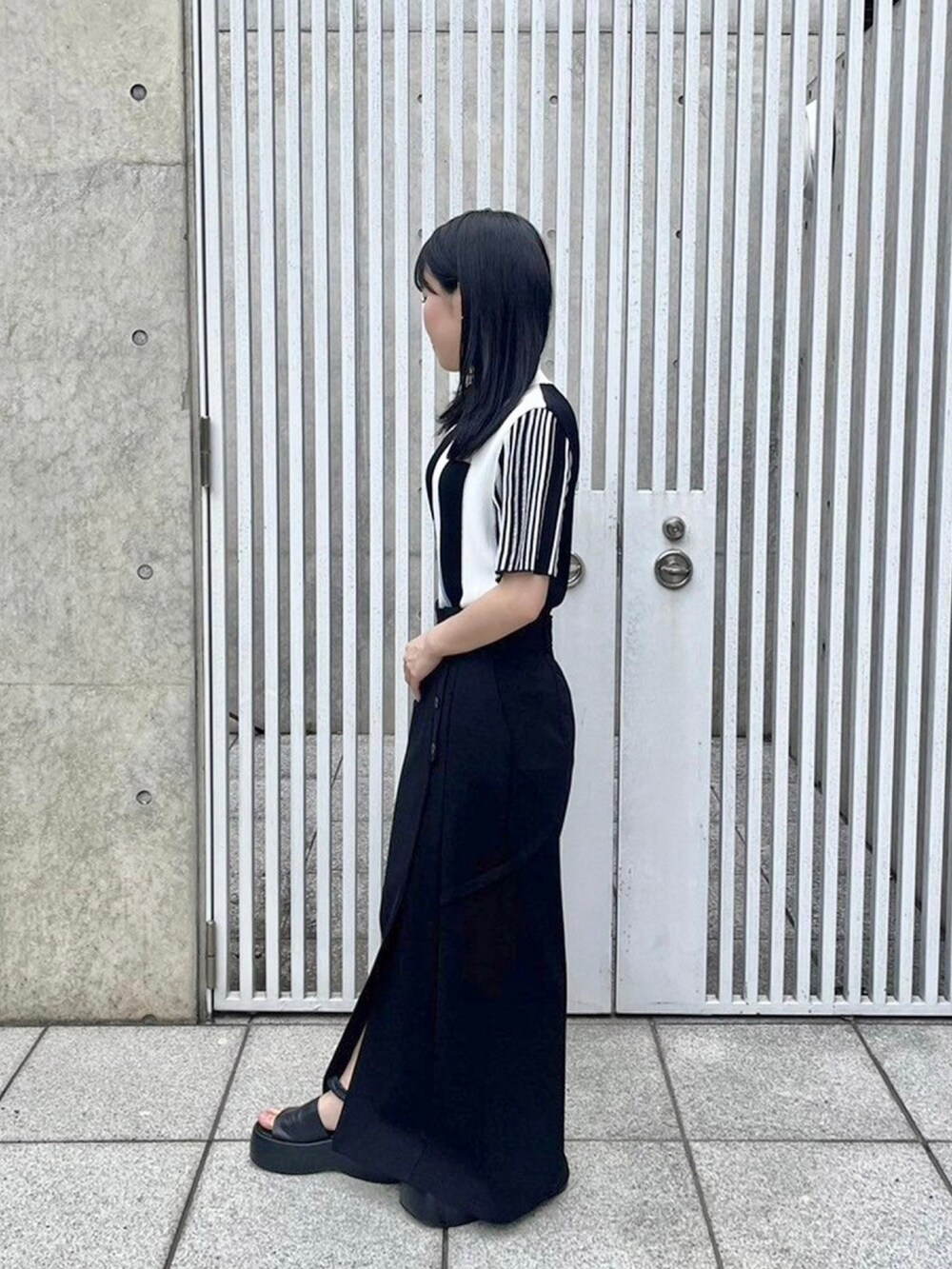 ブラック系のニット/セーター、ブラック系のスカートを着用したレディースの春コーディネートの2枚目の写真