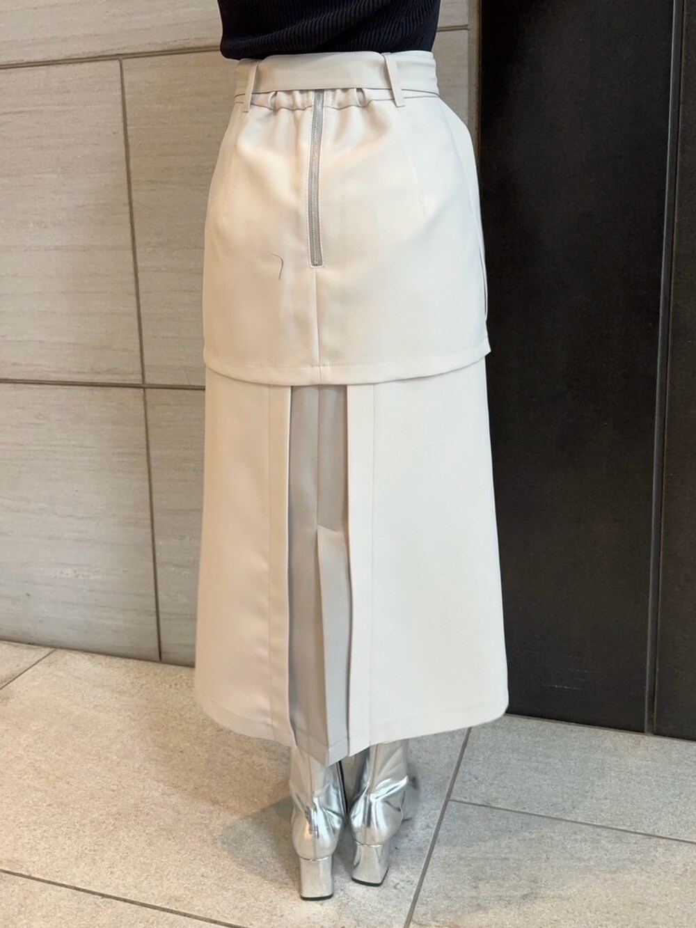 ベージュ系のスカート、ブラック系のニット/セーターを着用したレディースの春コーディネートの6枚目の写真