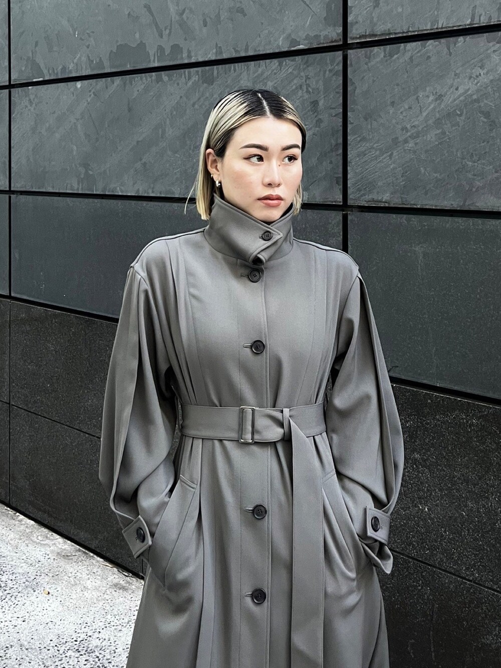 グレー系のトレンチコートを着用したレディースの秋コーディネートの3枚目の写真