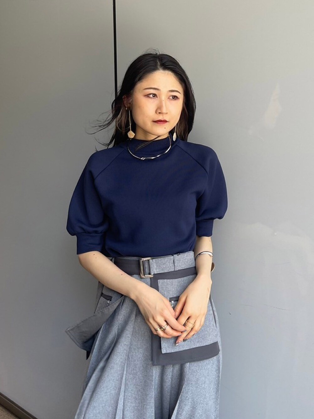 ブルー系のニット/セーター、グレー系のスカートを着用したレディースの夏コーディネートの3枚目の写真