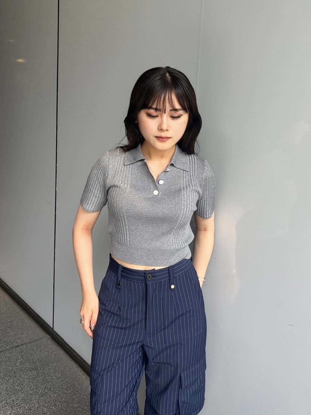 グレー系のポロシャツ、ブルー系のカーゴパンツを着用したレディースの夏コーディネートの2枚目の写真