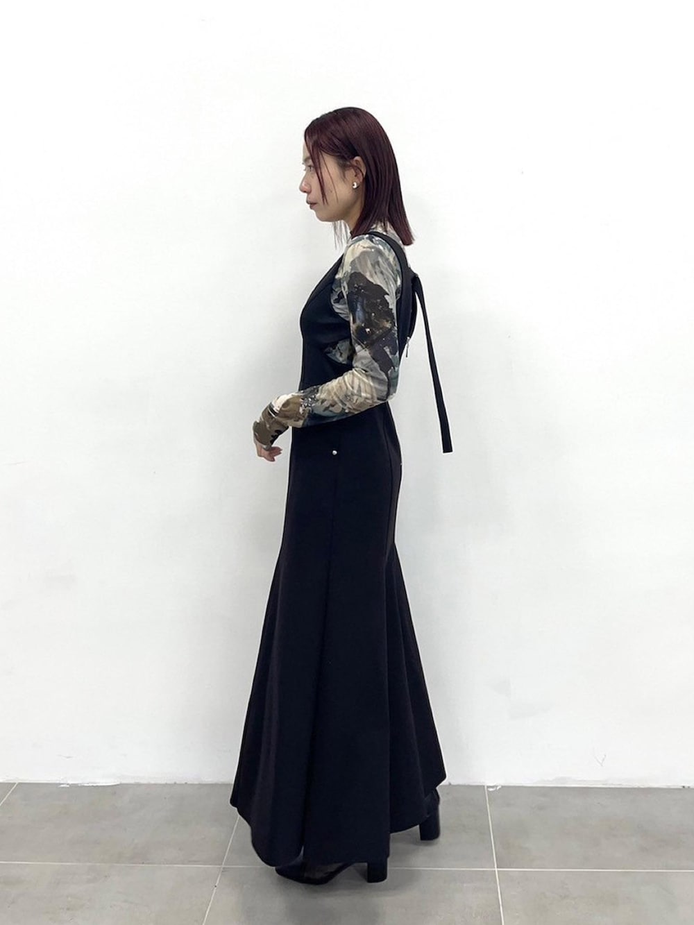 ブラック系のジャンパースカートを着用したレディースの春コーディネートの2枚目の写真