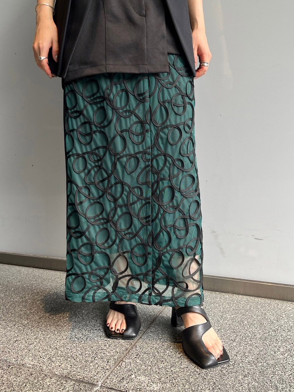 ブラック系のノーカラージャケット、グリーン系のスカートを着用したレディースの夏コーディネートの5枚目の写真