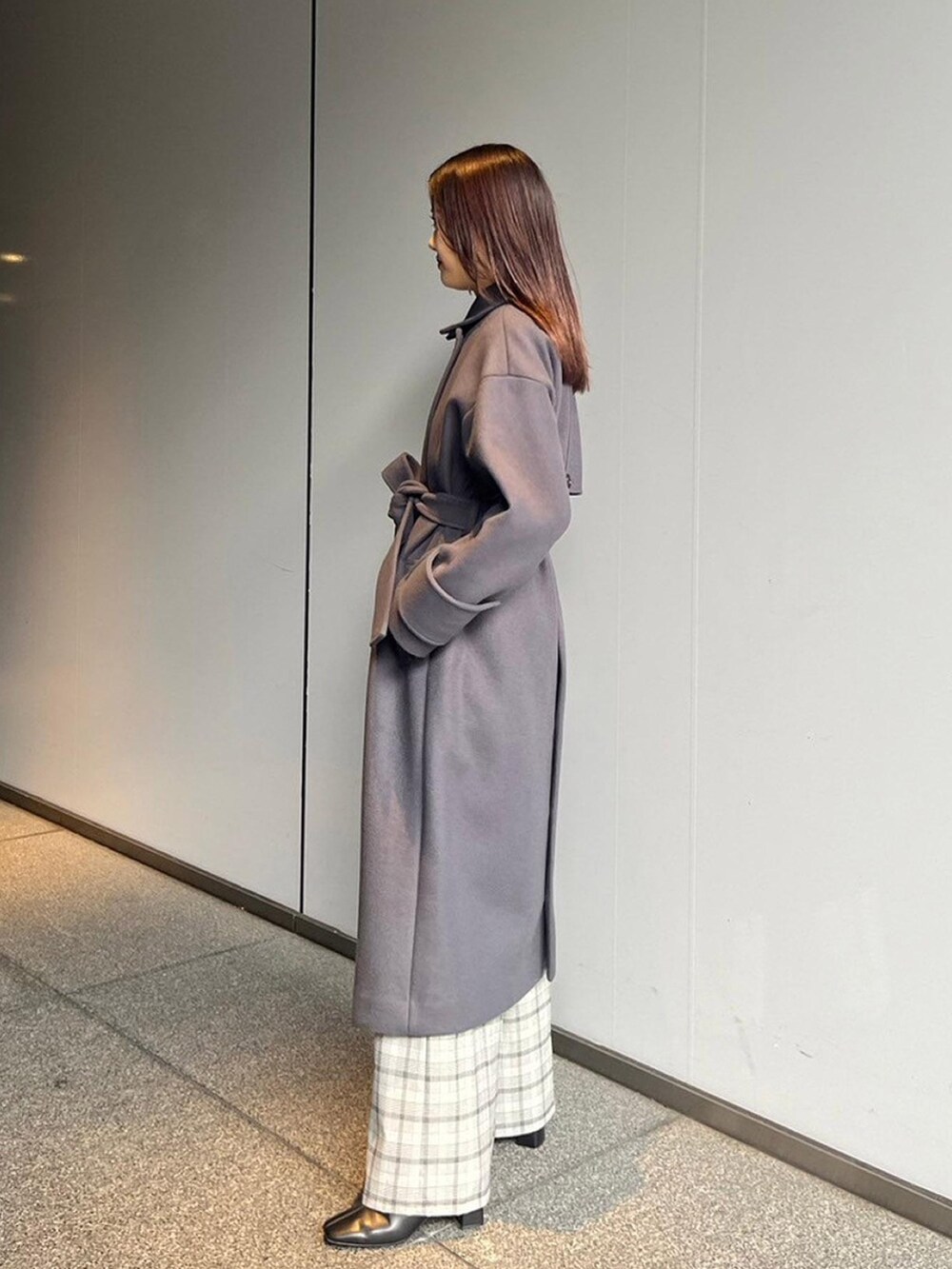 グレー系のステンカラーコートを着用したレディースの秋コーディネートの2枚目の写真