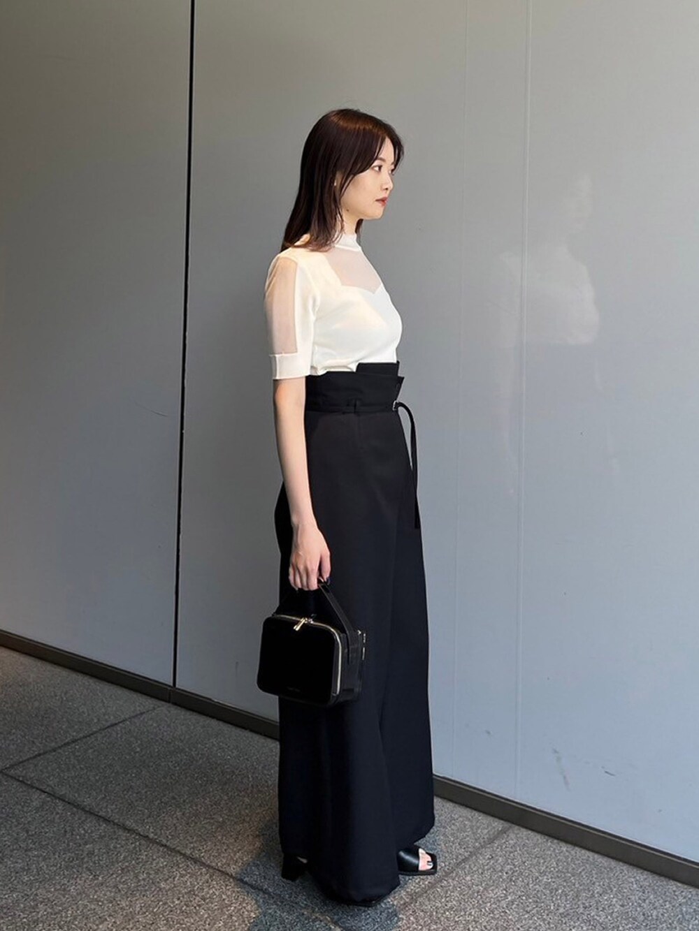 ホワイト系のニット/セーター、ブラック系のスラックスを着用したレディースの夏コーディネートの2枚目の写真