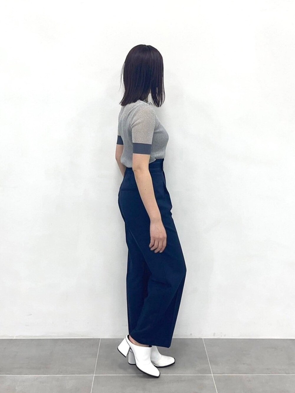 シルバー系のニット/セーター、ブルー系のスラックスを着用したレディースの春コーディネートの4枚目の写真