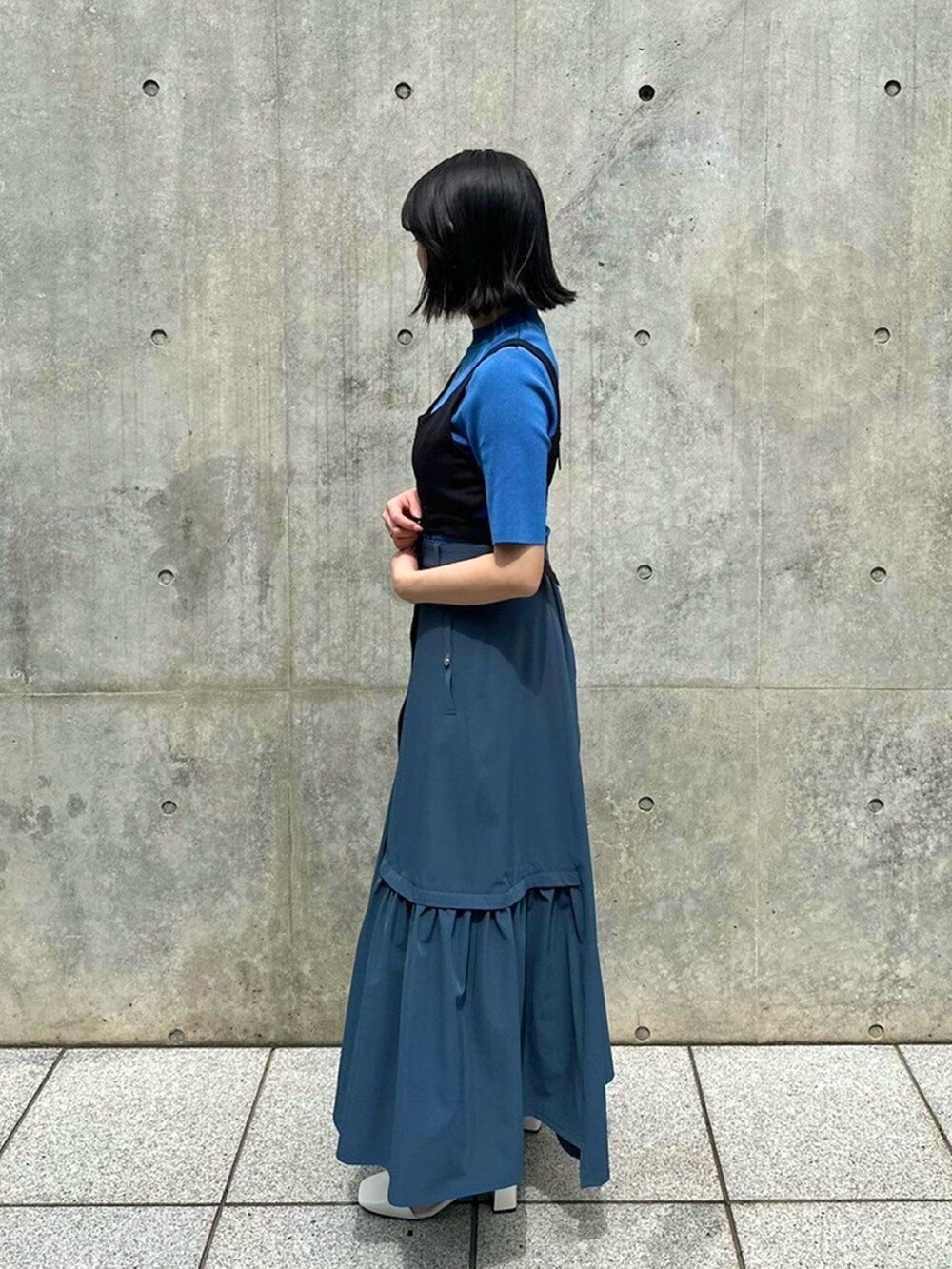 ブルー系のニット/セーター、ブラック系のベスト、グレー系のスカートを着用したレディースの春コーディネートの2枚目の写真