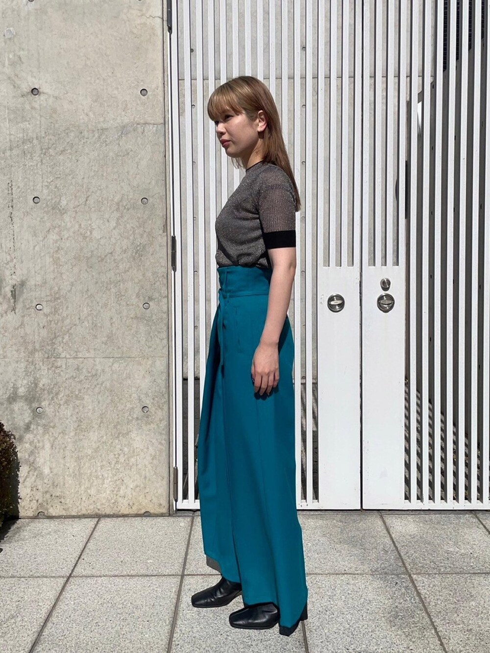 ゴールド系のニット/セーター、グリーン系のスラックスを着用したレディースの春コーディネートの2枚目の写真