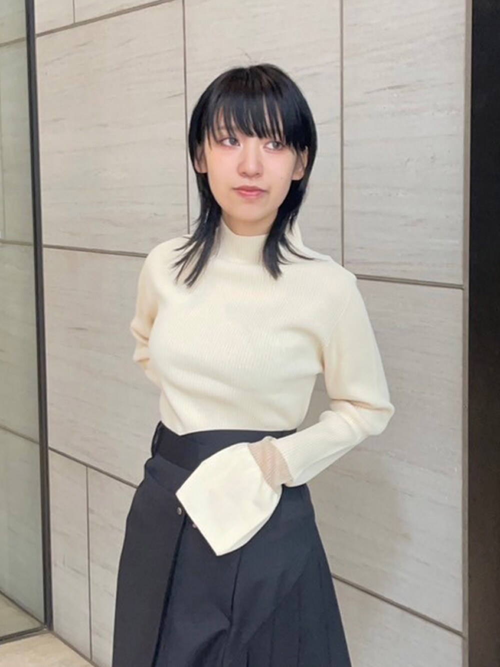 ベージュ系のニット/セーター、ブラック系のスカートを着用したレディースの春コーディネートの5枚目の写真