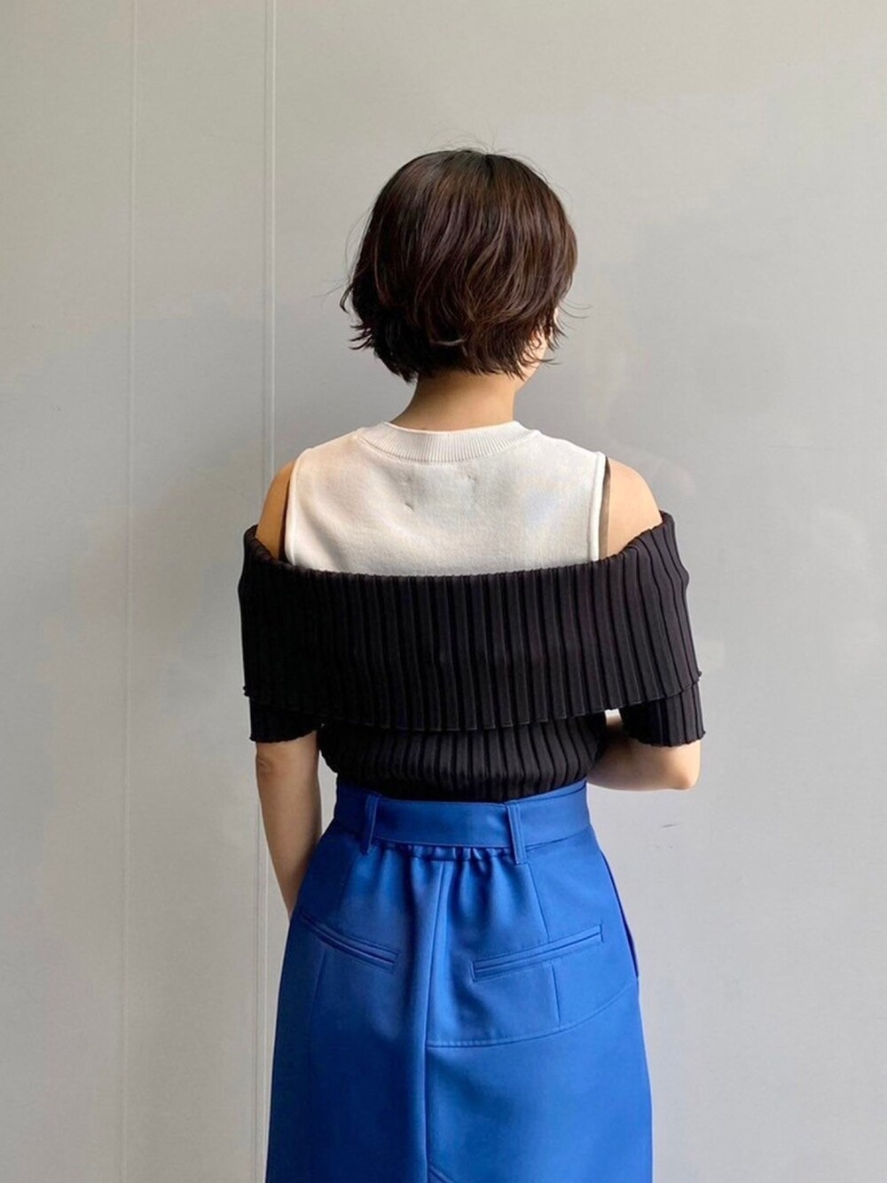 ブラック系のニット/セーター、ブルー系のスカートを着用したレディースの春コーディネートの6枚目の写真