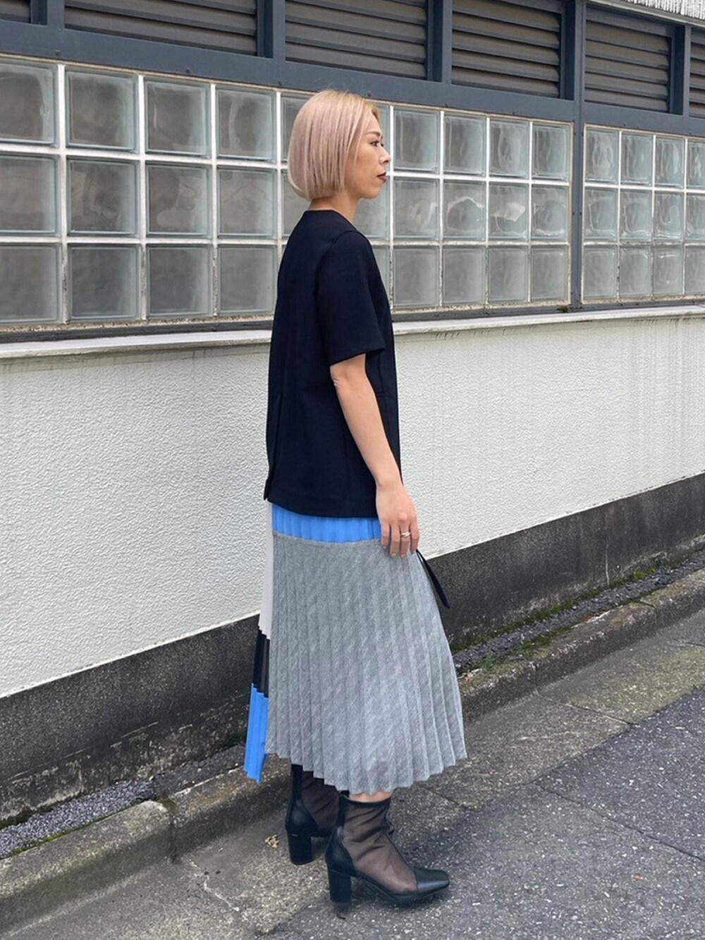 ブラック系のノーカラージャケット、ブルー系のスカートを着用したレディースの春コーディネートの4枚目の写真