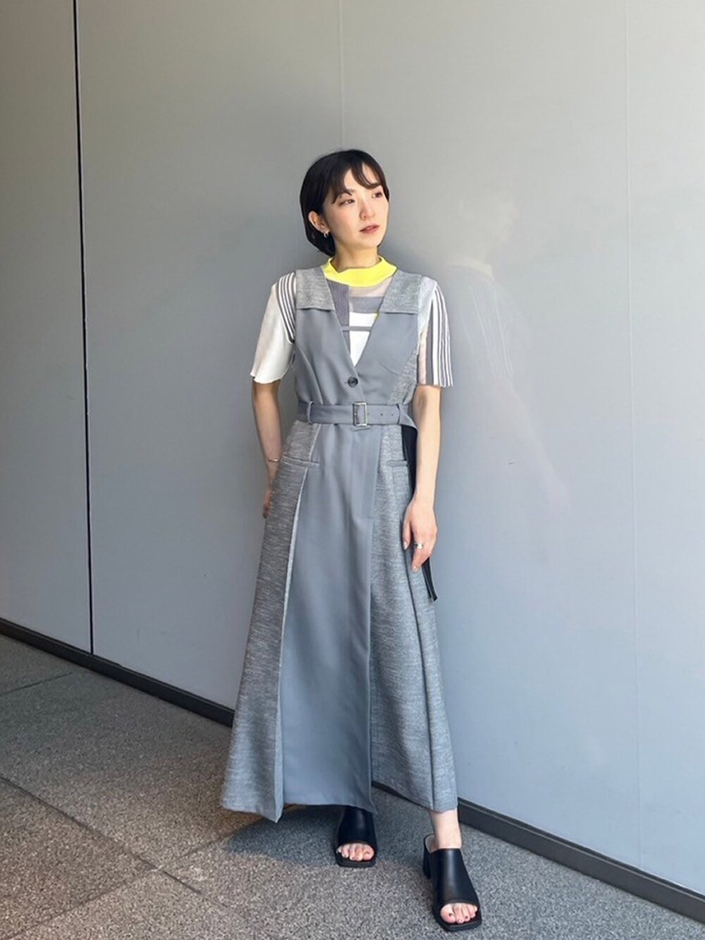 グレー系のジャンパースカート、イエロー系のニット/セーターを着用したレディースの夏コーディネートの2枚目の写真