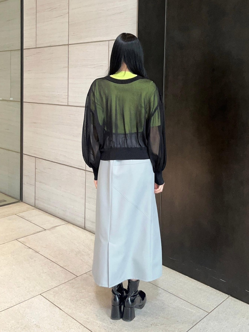 グレー系のスカート、ブラック系のカーディガン/ボレロ、グリーン系のニット/セーターを着用したレディースの春コーディネートの3枚目の写真